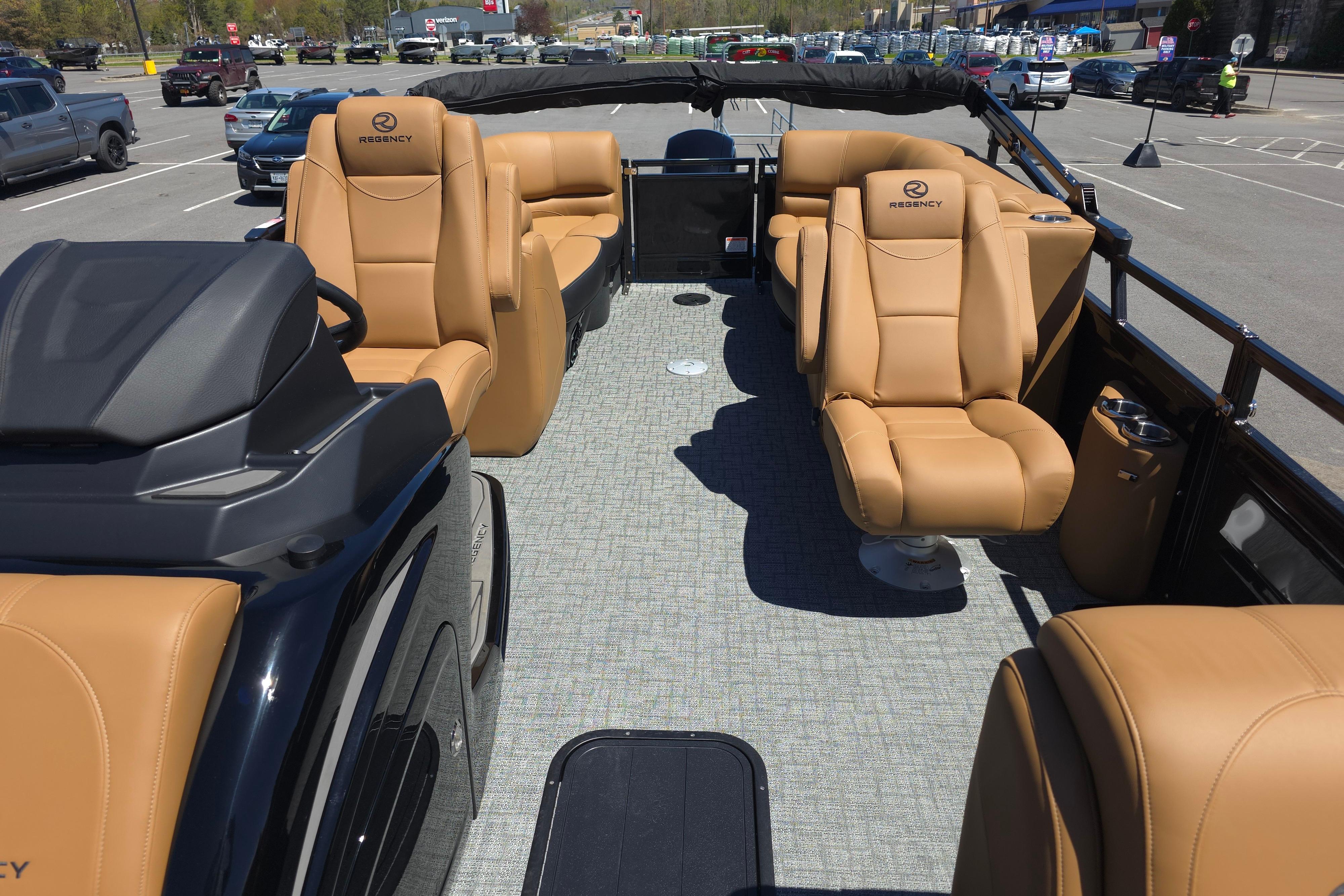 Luxurious 2026 Regency 230 DL pontoon boat with tan leather seating in a parking lot.