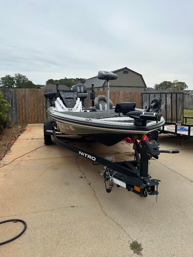 A 2020 Nitro Z18 boat on a trailer in a yard, surrounded by a wooden fence.