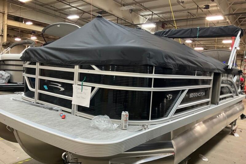 2026 Bennington 22 SSRSF pontoon boat in a warehouse, covered and ready for display.