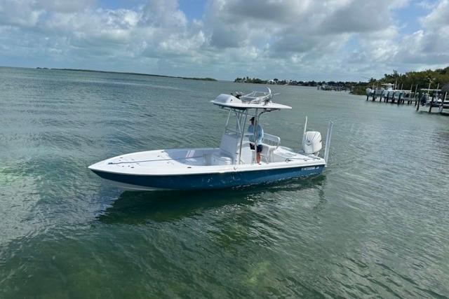 2025 Contender 26 Bay boat cruising on calm, clear waters under a partly cloudy sky.