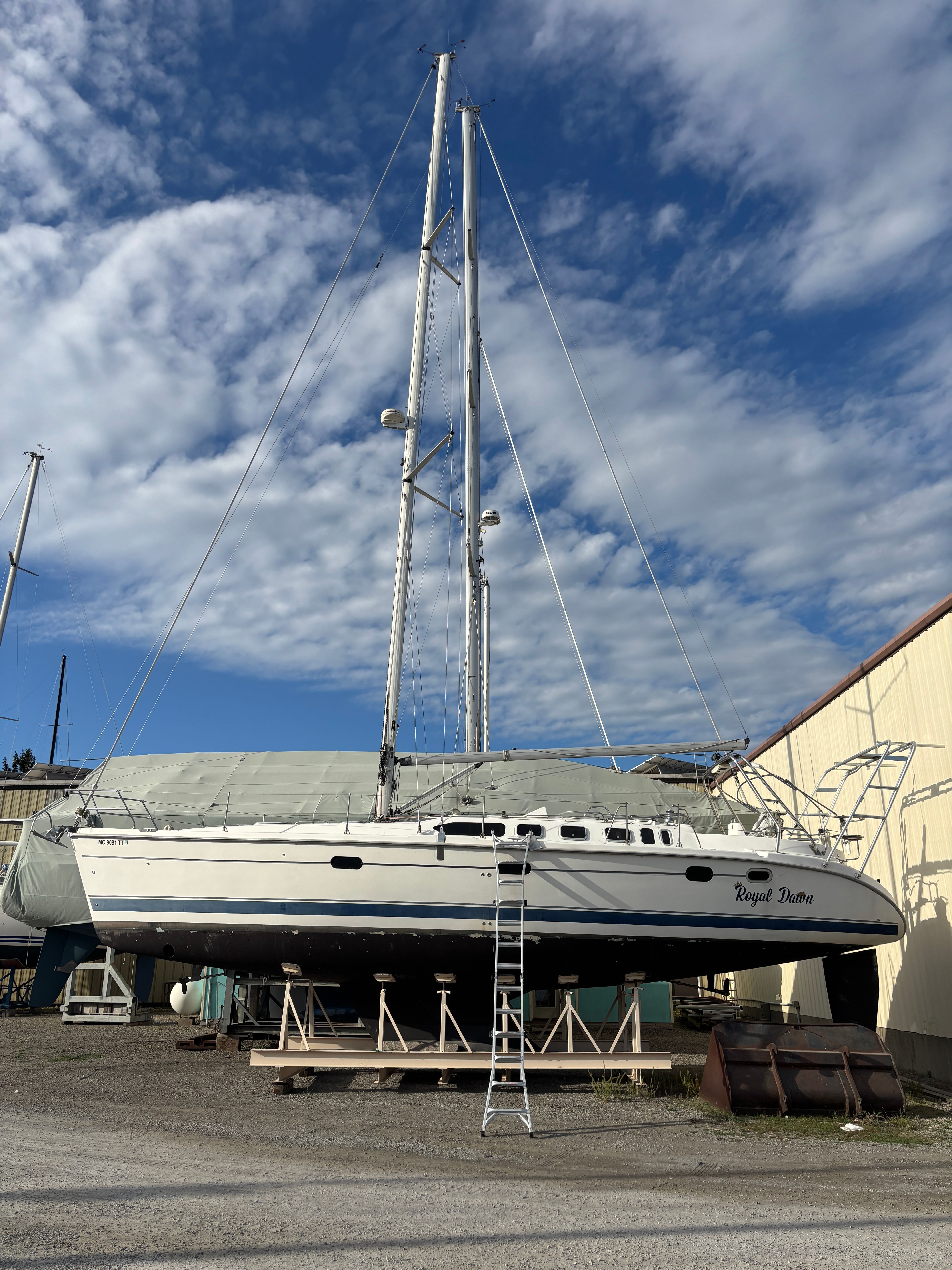 Sailboat Hunter 460, 2001 model, on dry dock under a partly cloudy sky.