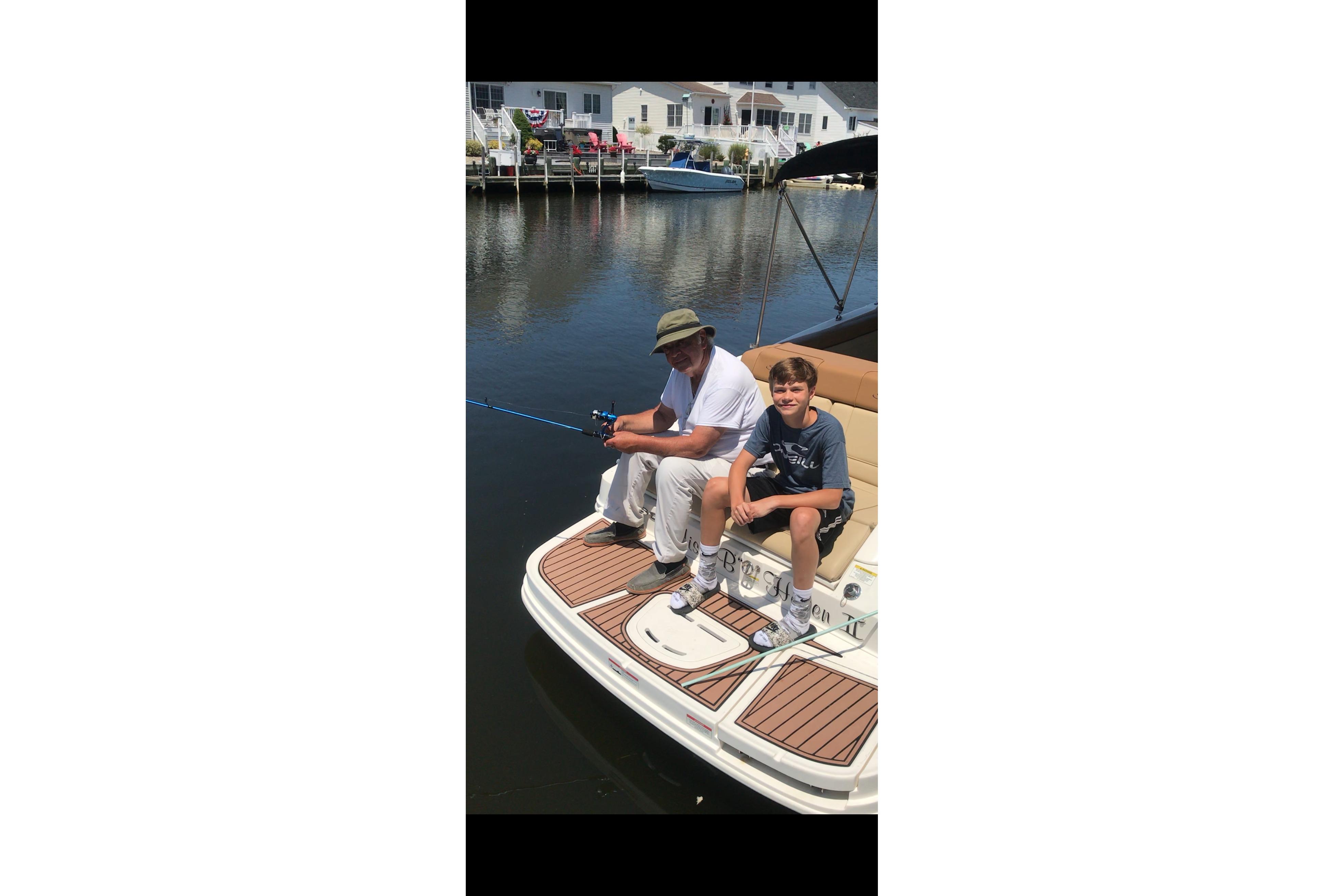 Two people fishing on a 2014 Sea Ray 260 Sundeck boat.