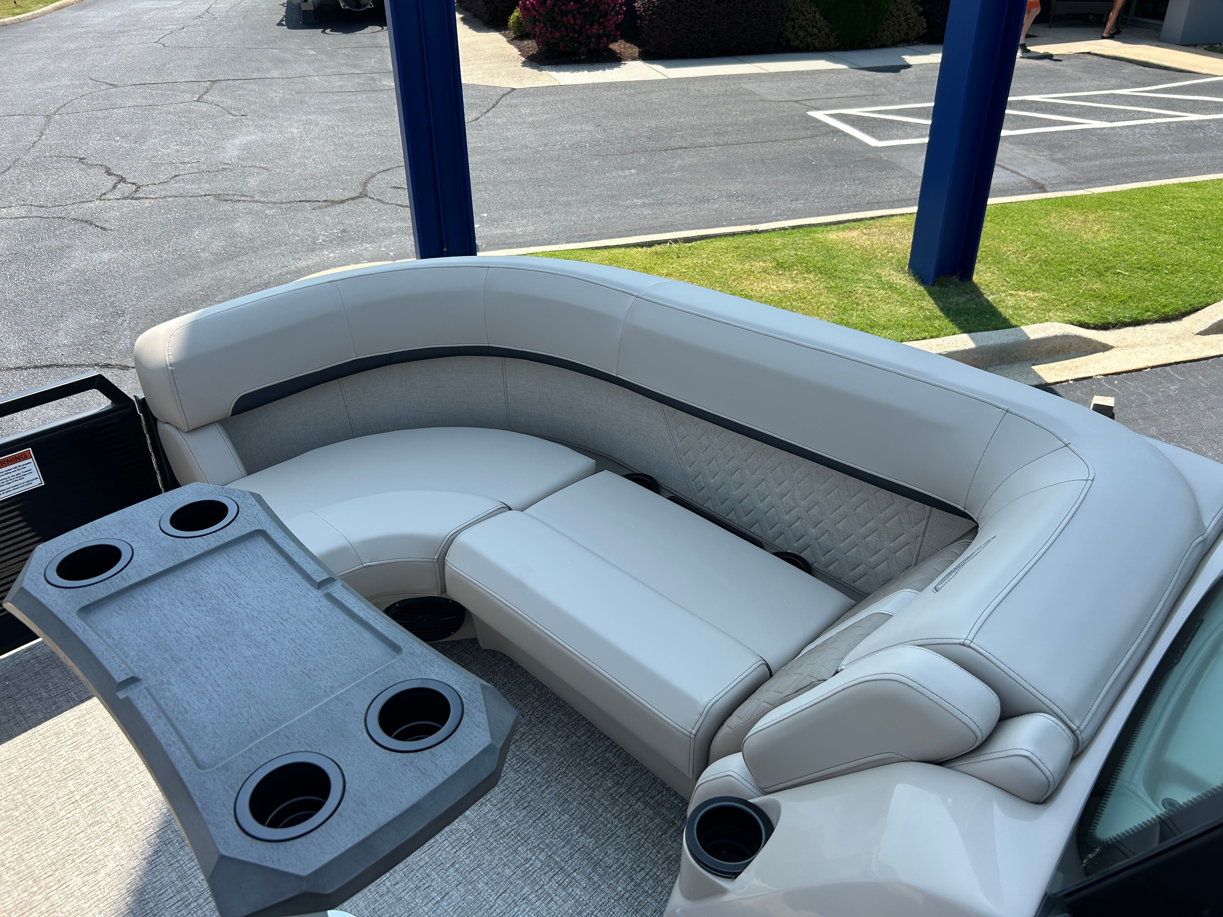 The image shows a luxurious, cushioned seating area on a boat with a table and cup holders.