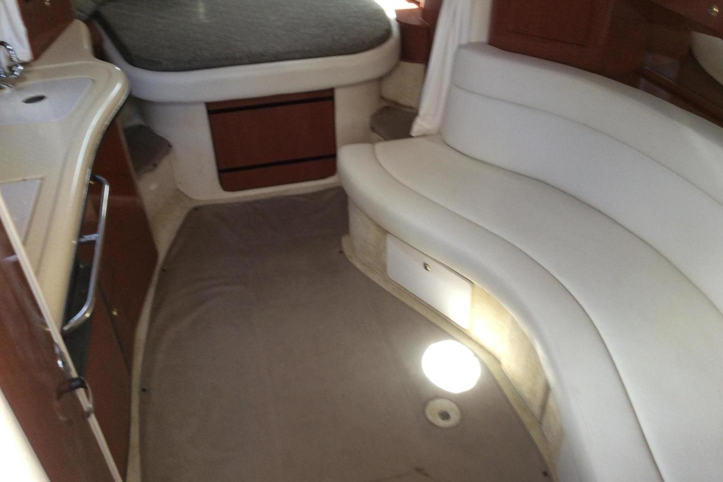 2003 Sea Ray 320 Sundancer interior with curved seating and compact kitchenette.