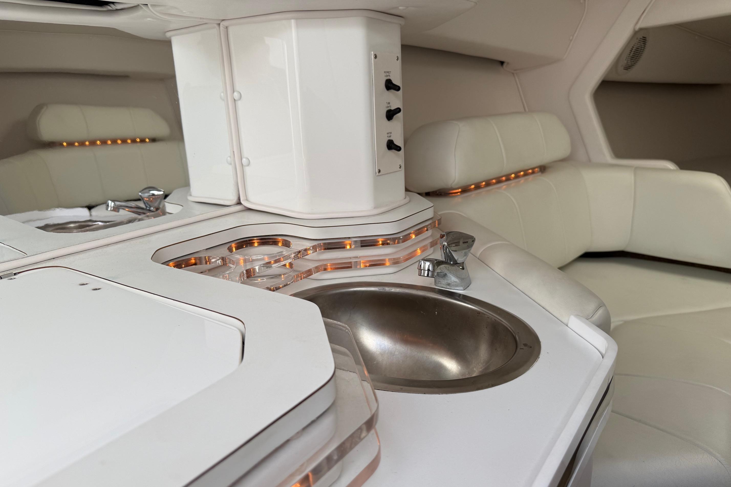 Interior of a 1998 Fountain 35 Lightning boat with white seating and a compact sink area.