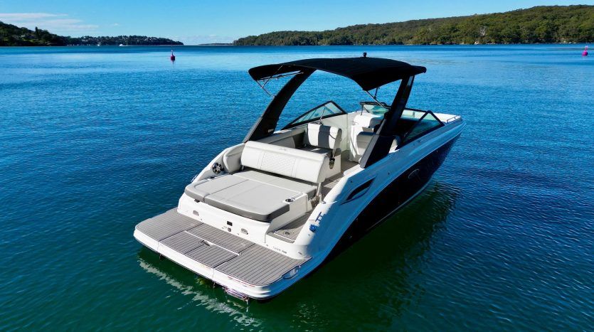 2022 Sea Ray SDX 250 on calm water with wooded shoreline in the background.