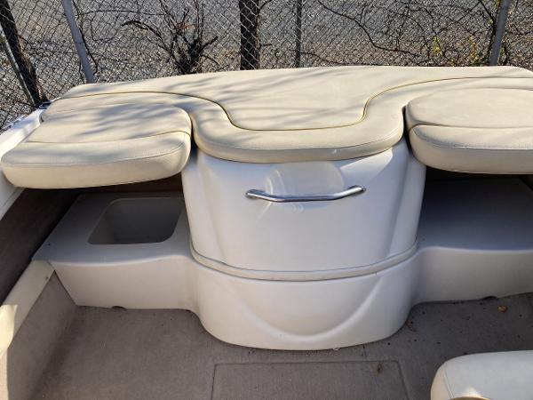 2001 Sea Ray 180 Bow Rider interior seating with beige cushions and storage compartment.