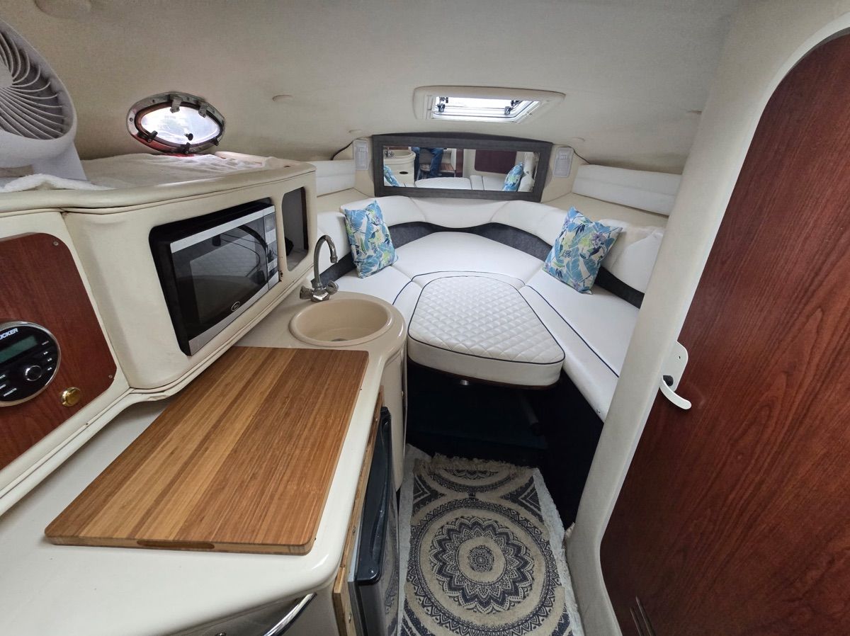 Interior of a Sea Ray Sundancer 260 with cozy seating area and kitchenette.