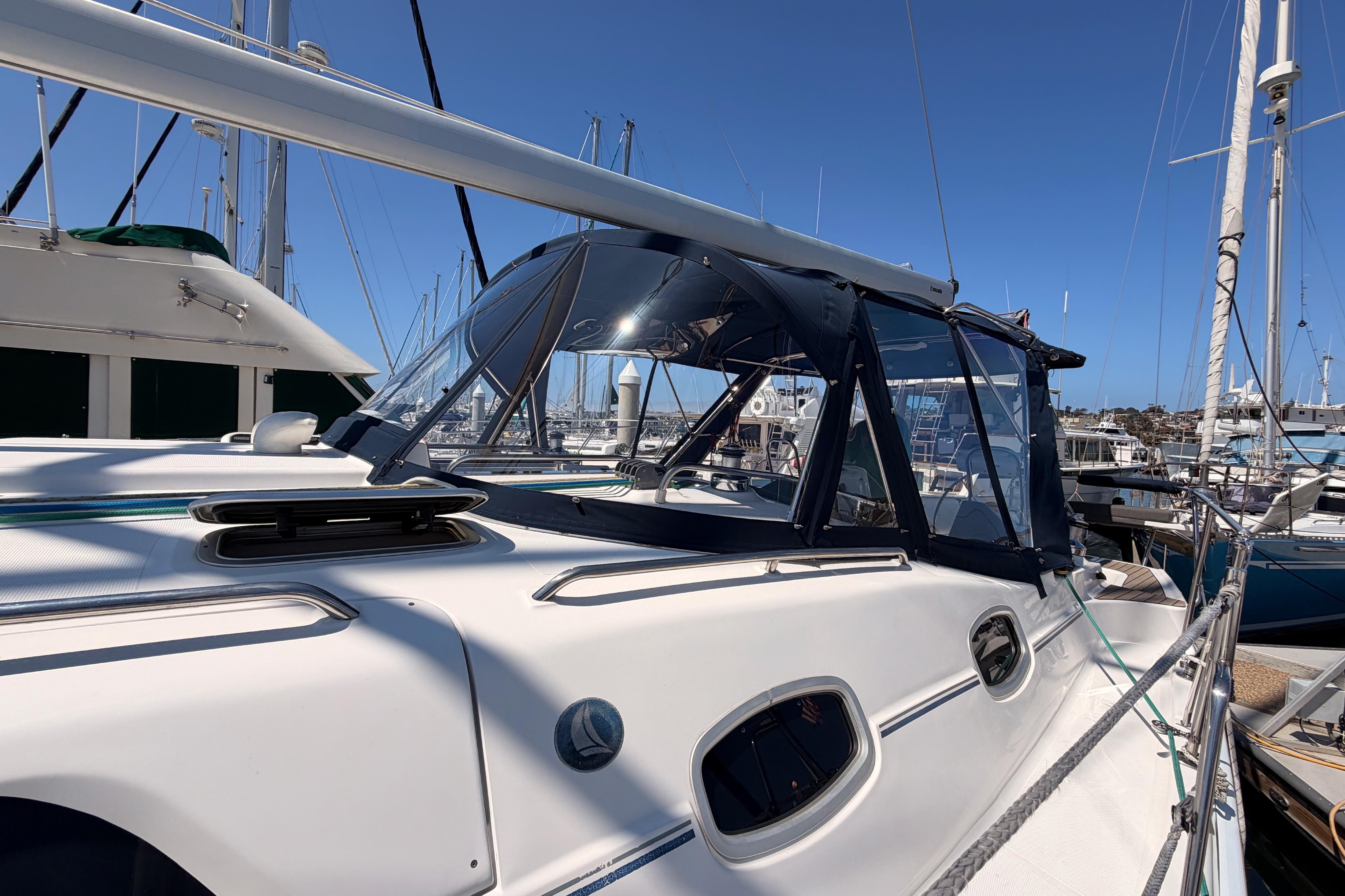 2008 Hunter 45 Deck Salon sailboat docked in marina, featuring sleek design and blue canopy.