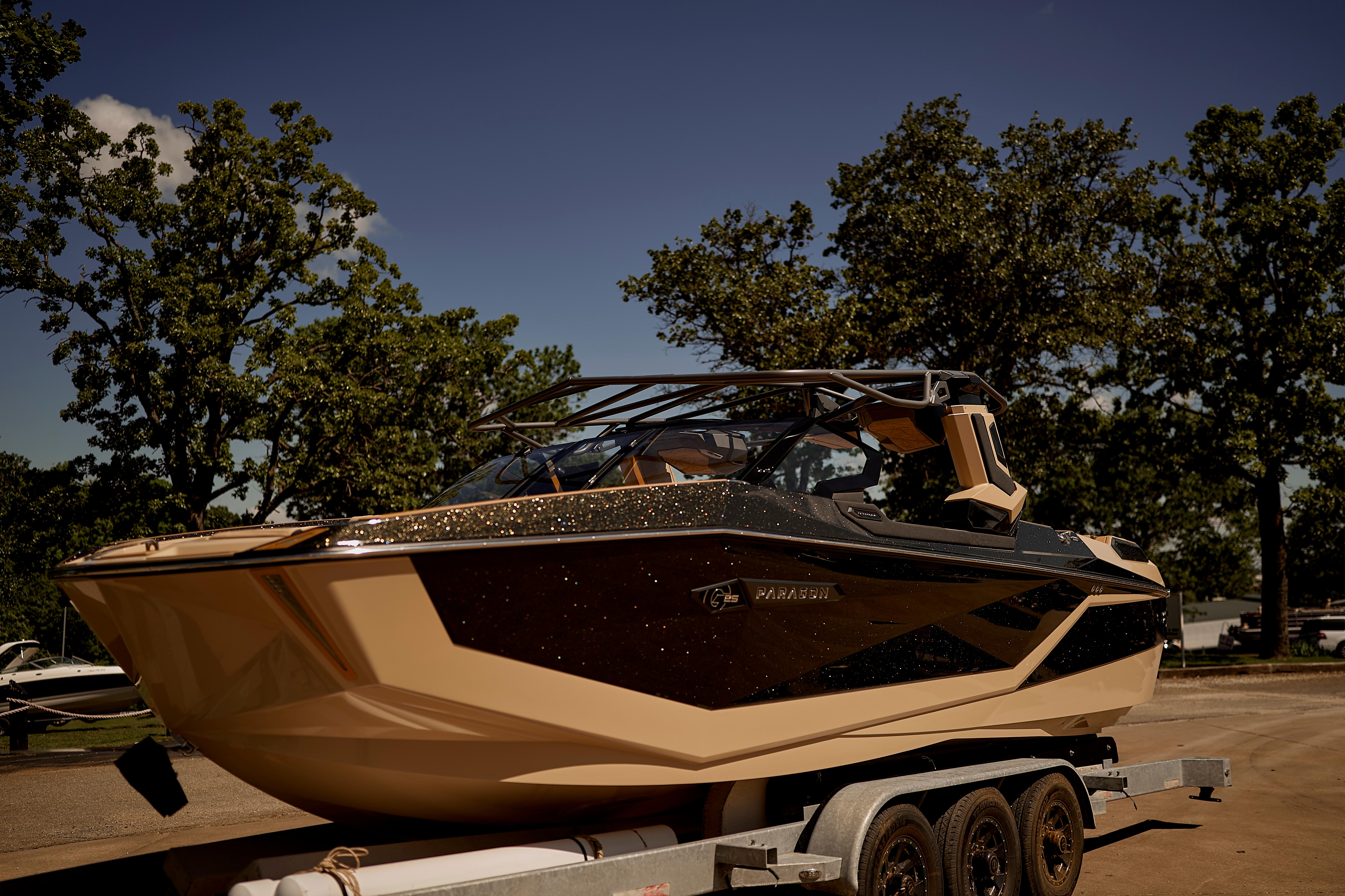 2025 Nautique Super Air Nautique G25 Paragon boat on trailer, surrounded by trees.