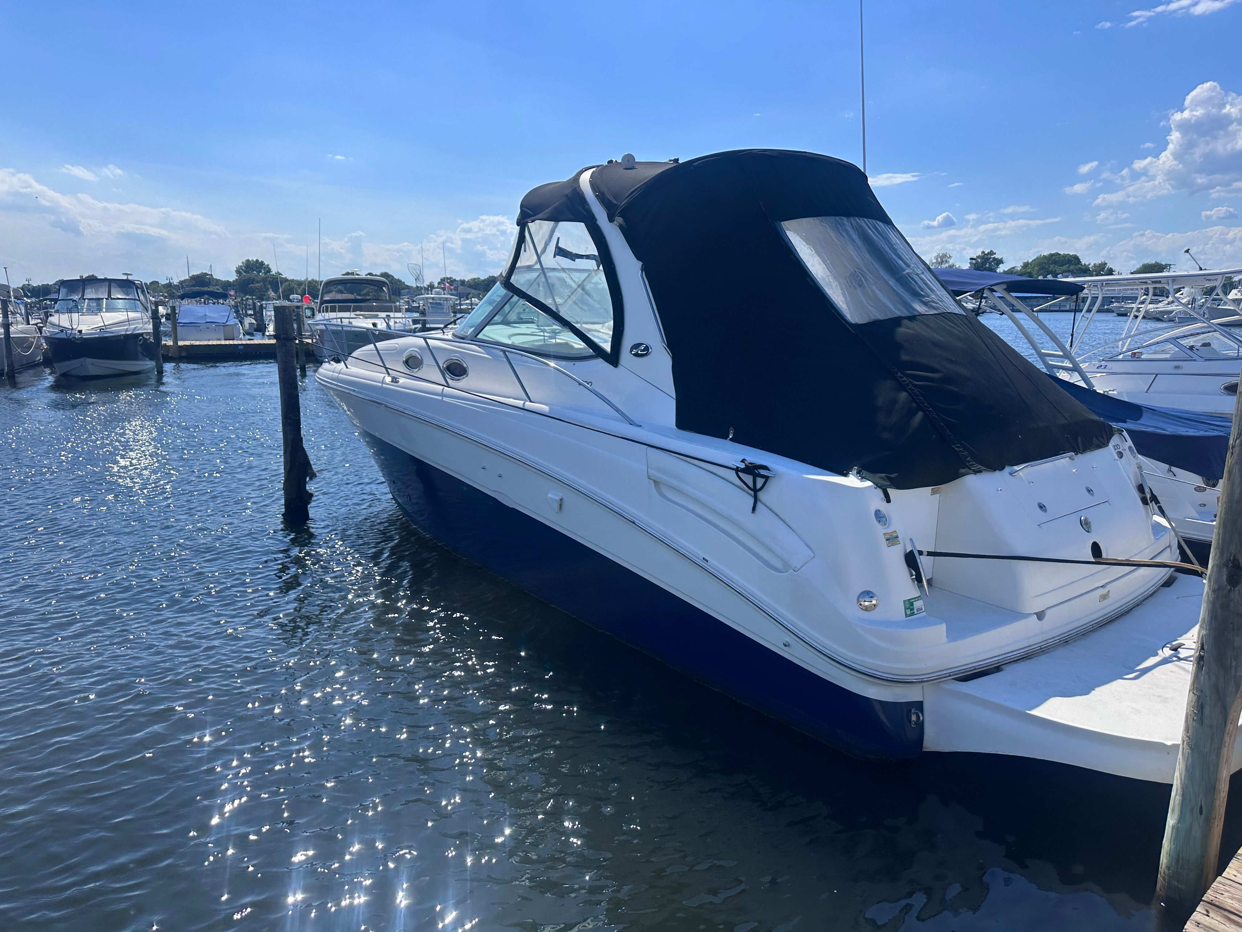 A 2002 Sea Ray 300 Sundancer is docked in the water, surrounded by other boats.