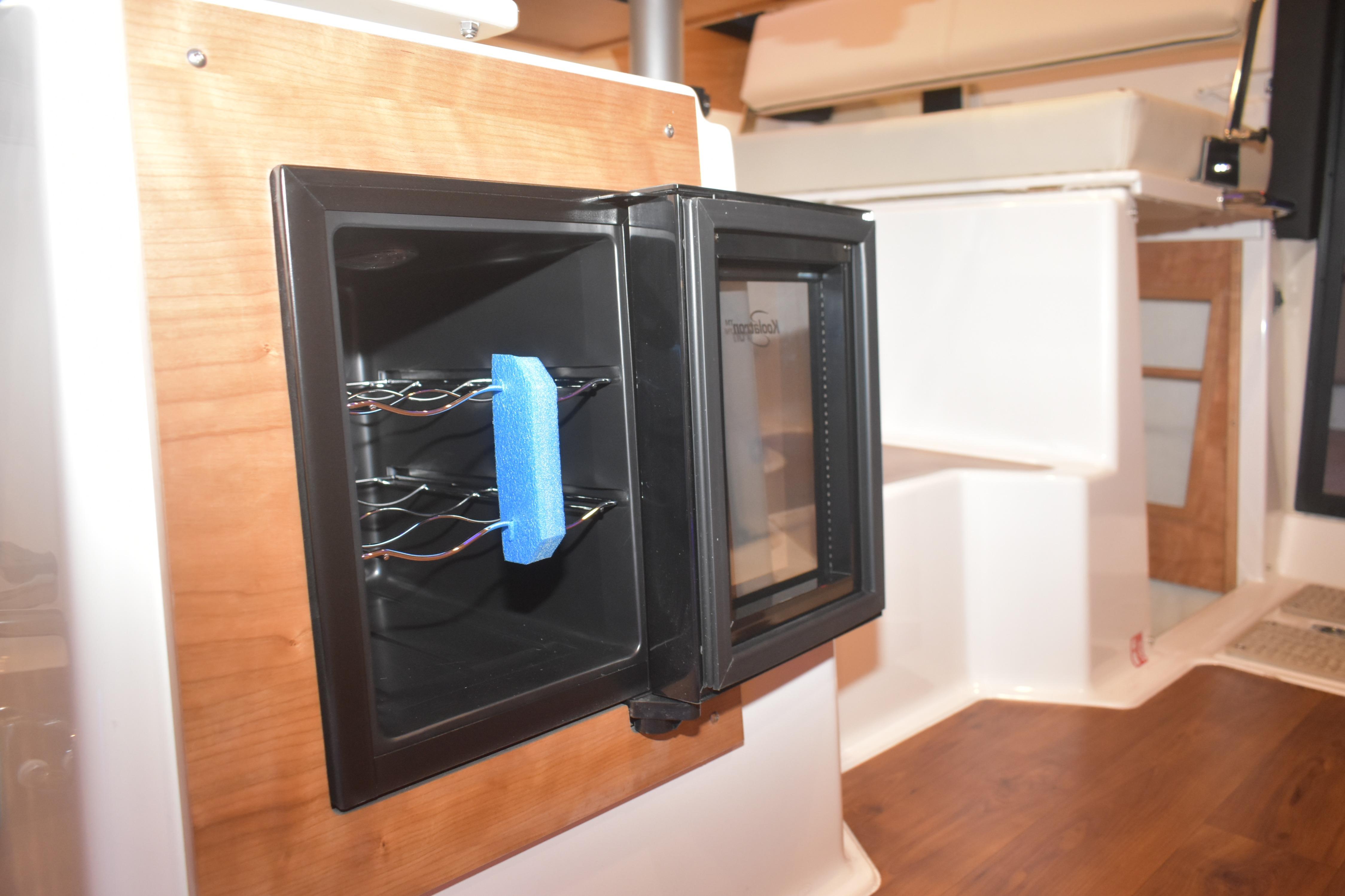 Open mini fridge inside 2026 Cutwater C-32 CB boat interior, featuring wooden accents.