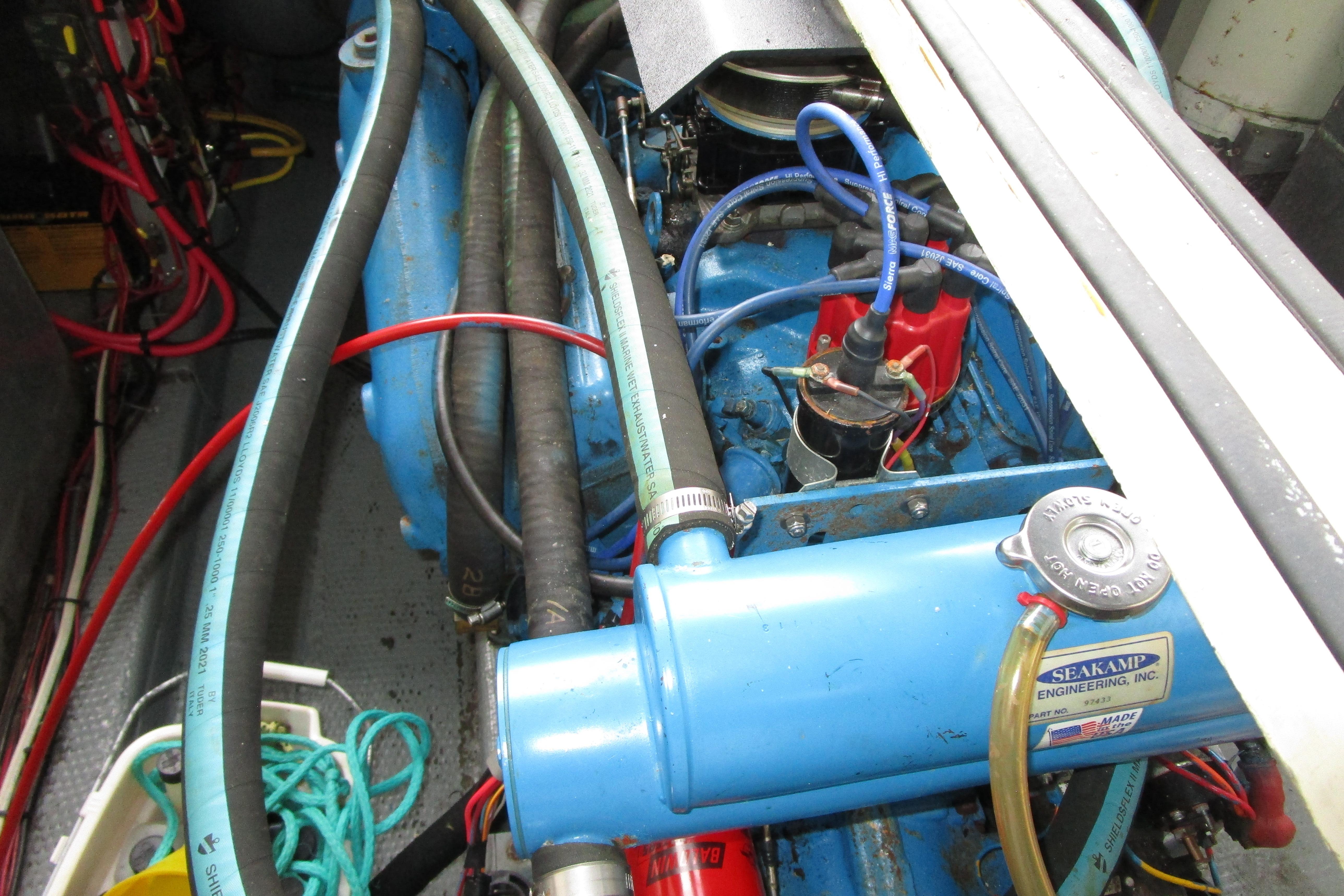 Engine compartment of a 1984 Tollycraft 26 Sedan boat, featuring hoses and wiring.