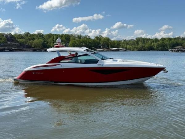 2022 Cobalt A36BR boat in red, cruising on a lake under a partly cloudy sky.