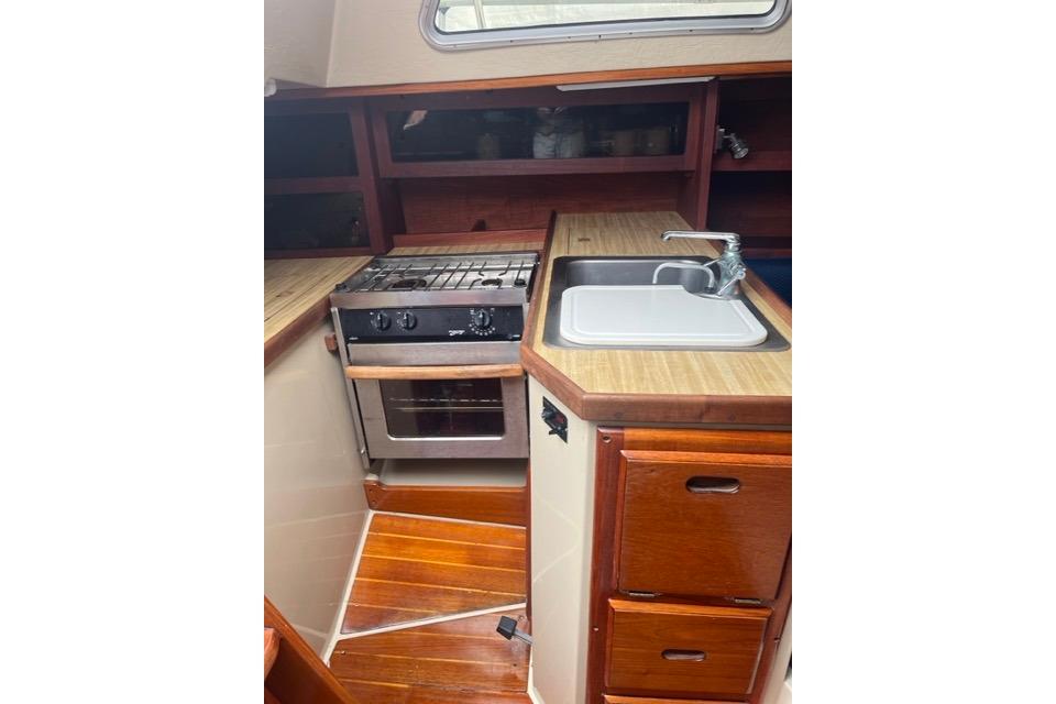 1982 Catalina 38 yacht kitchen with stove, sink, and wooden cabinetry.