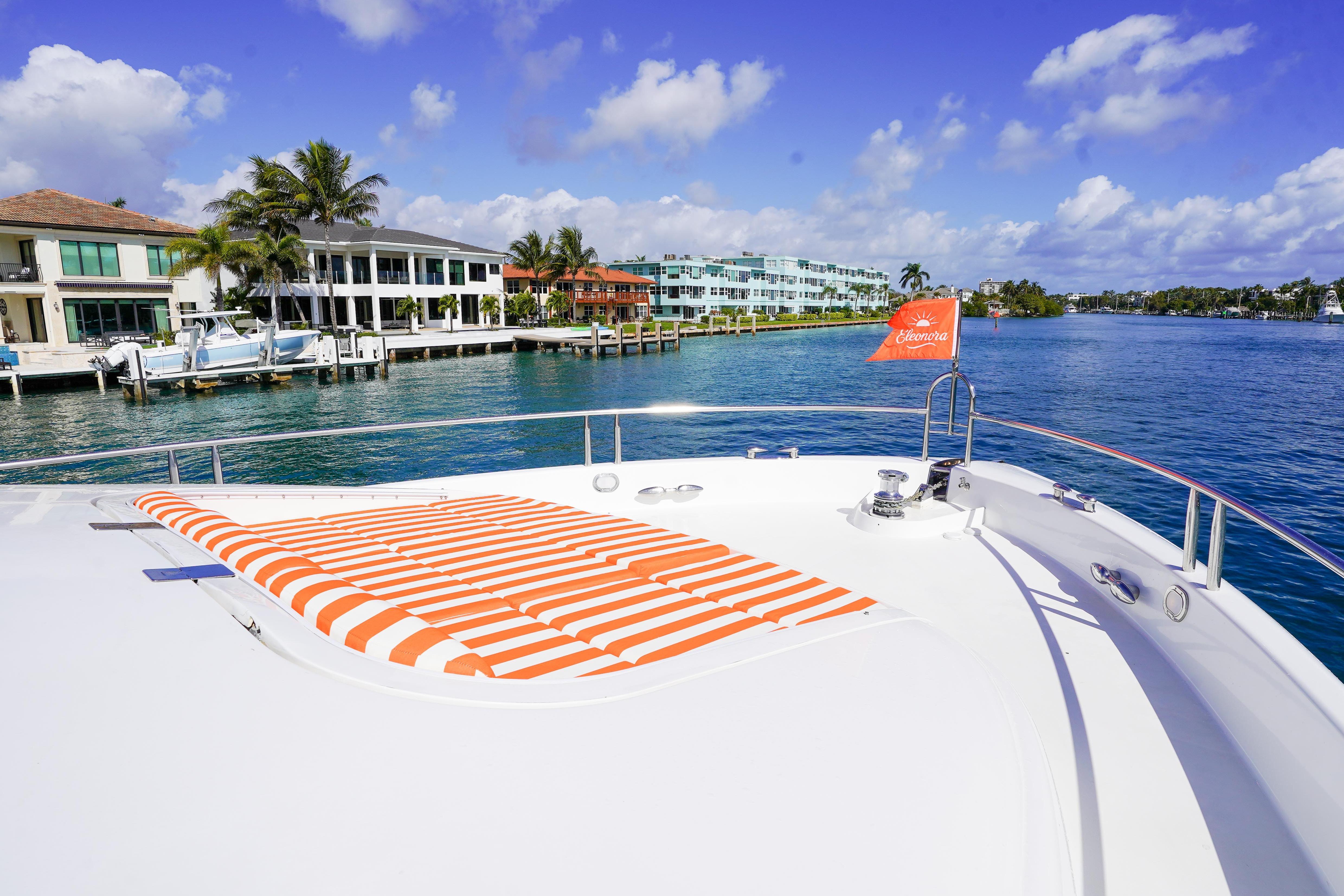 2004 Lazzara 80 SL yacht with striped sunbed, docked near waterfront homes.
