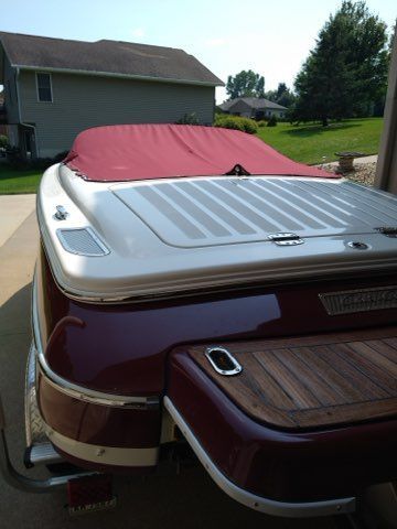 A 2006 Chris-Craft Speedster 20 with a red cover, parked in a driveway.