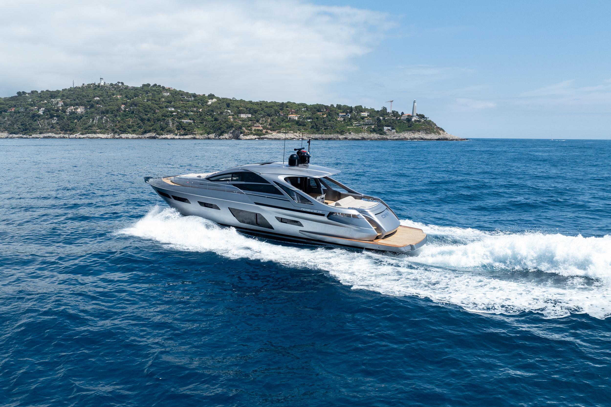 2024 Pershing 7X yacht cruising on open sea near a lush island.
