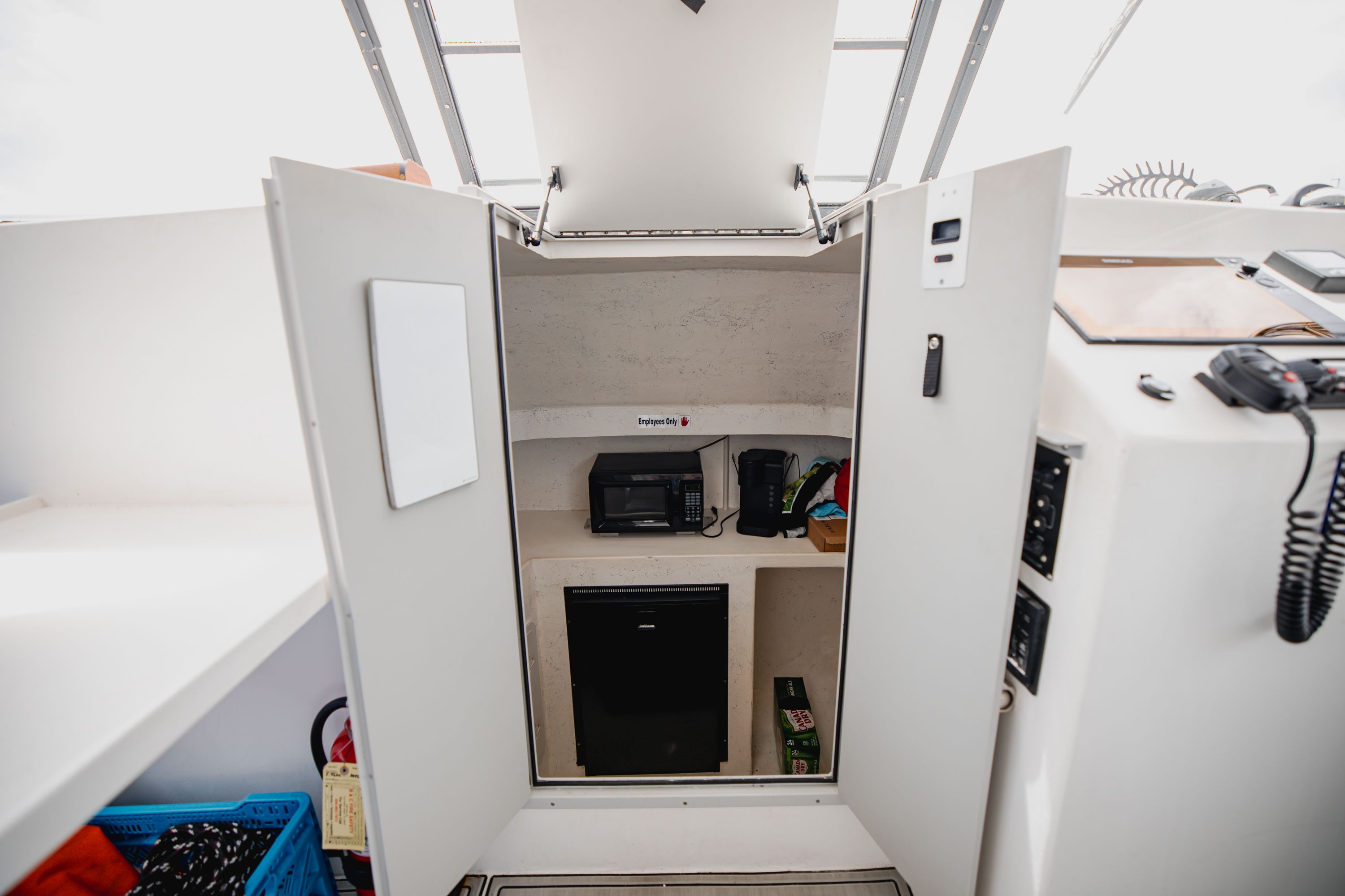 Interior of a boat with storage, a refrigerator, and appliances.
