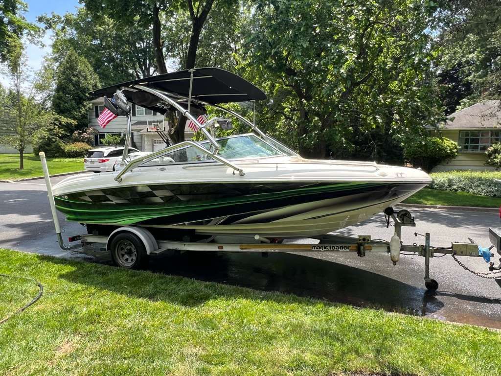 A 1997 Sea Ray 190 Bow Rider on a trailer in a green residential area.