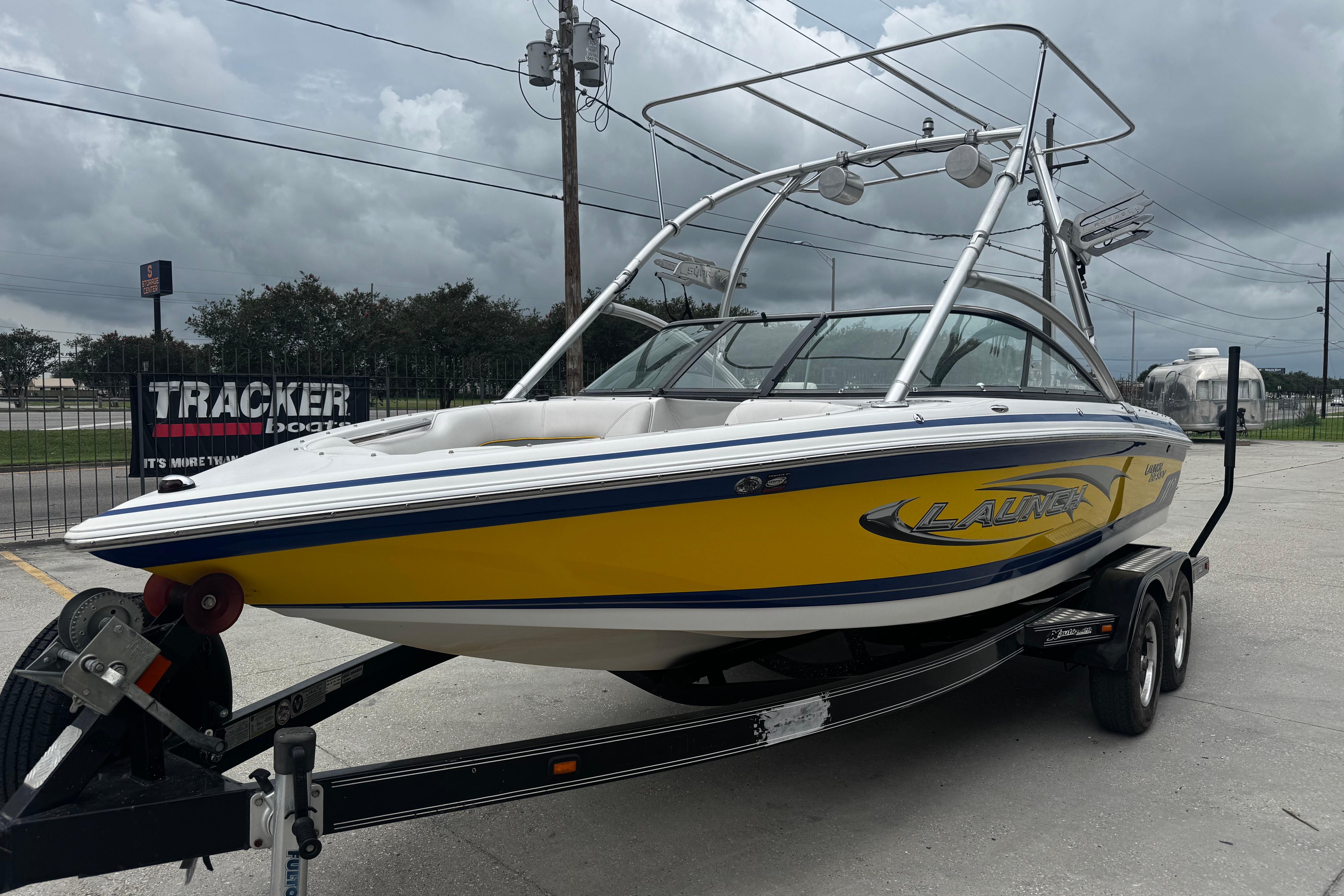 2006 Supra Launch 22 SSV boat on trailer, yellow and white design, overcast sky.