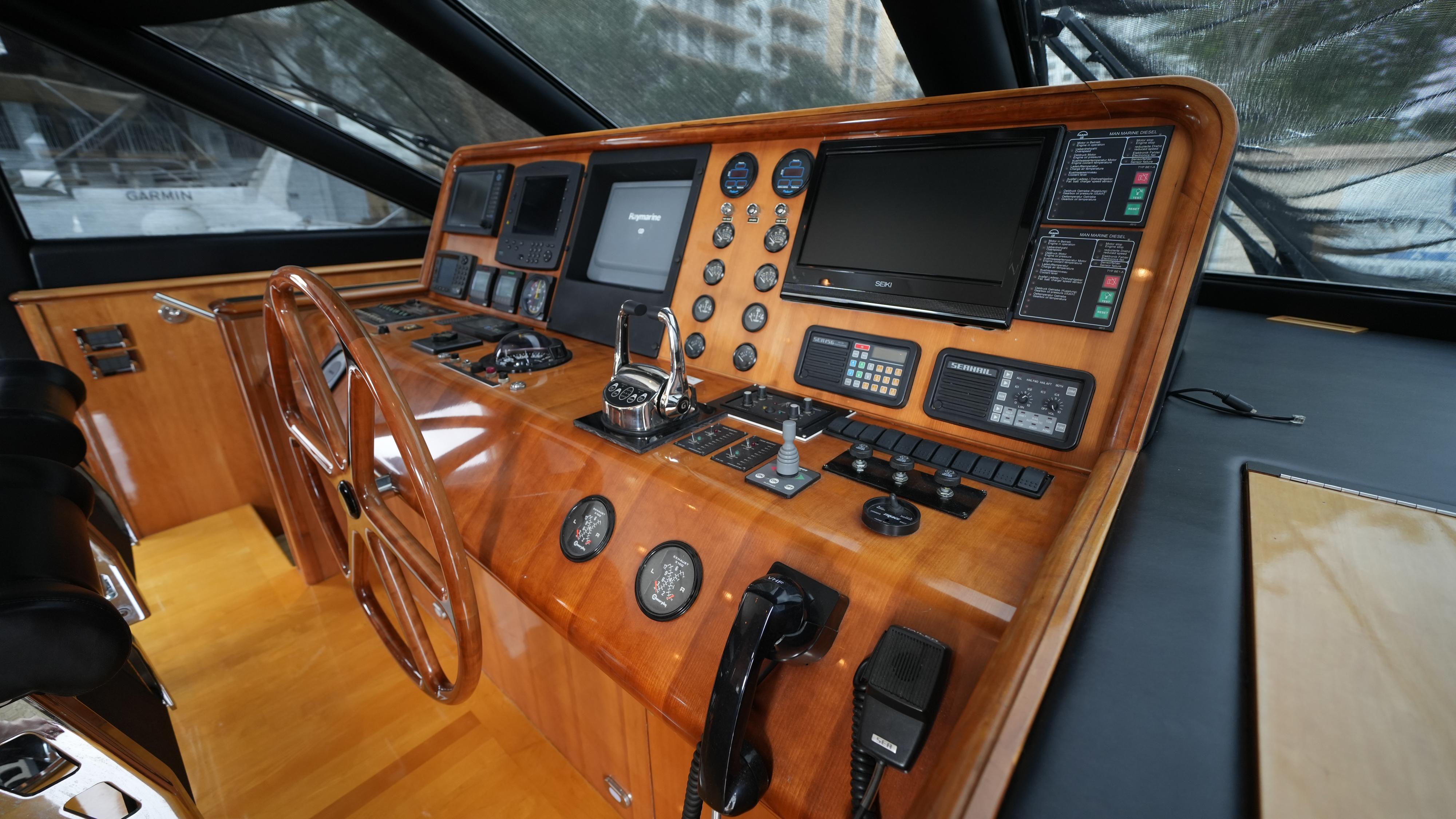 Helm station of 2002 Queenship 70 Baretta yacht with wooden dashboard and modern navigation equipment.