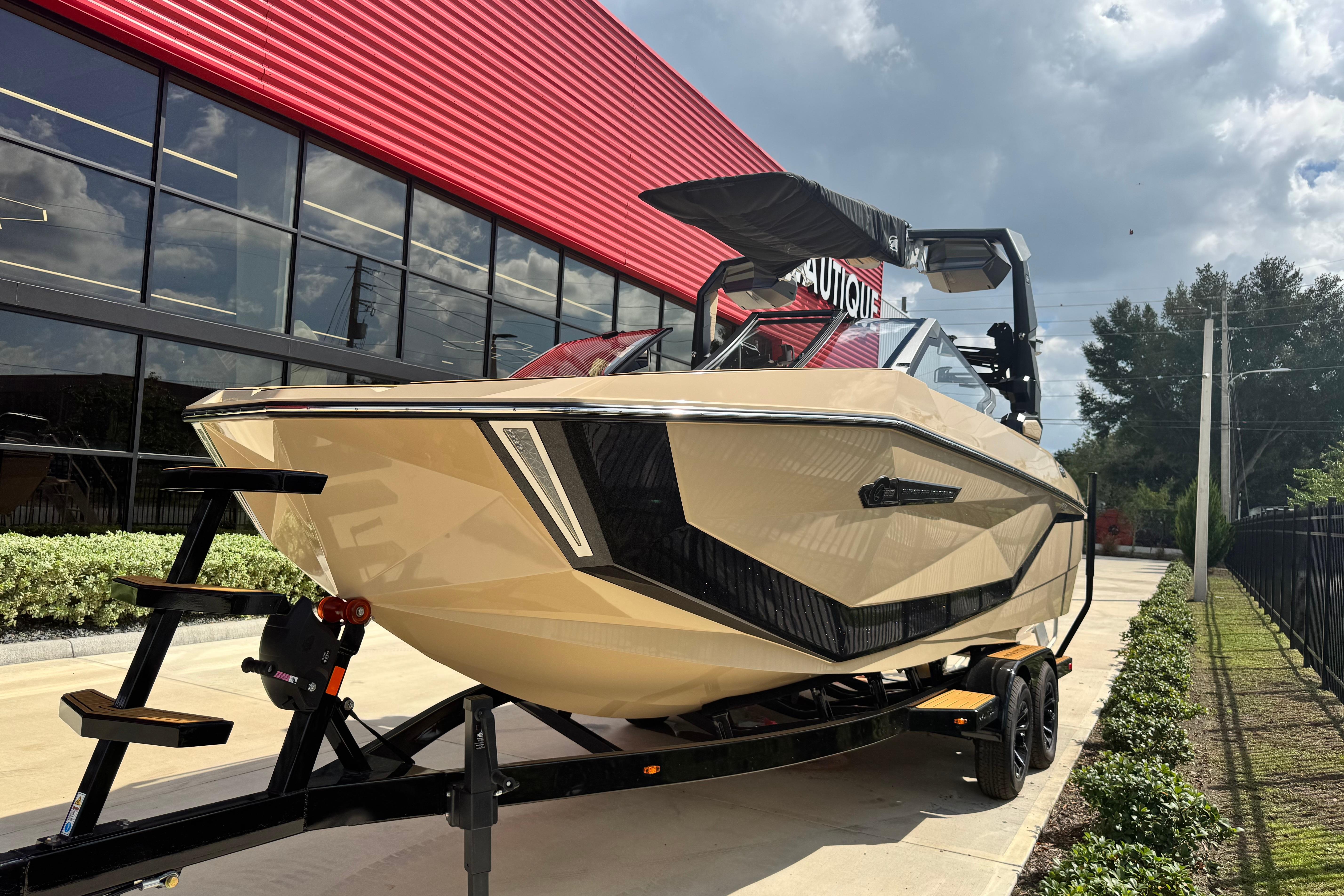 2026 Nautique Super Air Nautique G23 Paragon boat on trailer, parked outside a modern building.