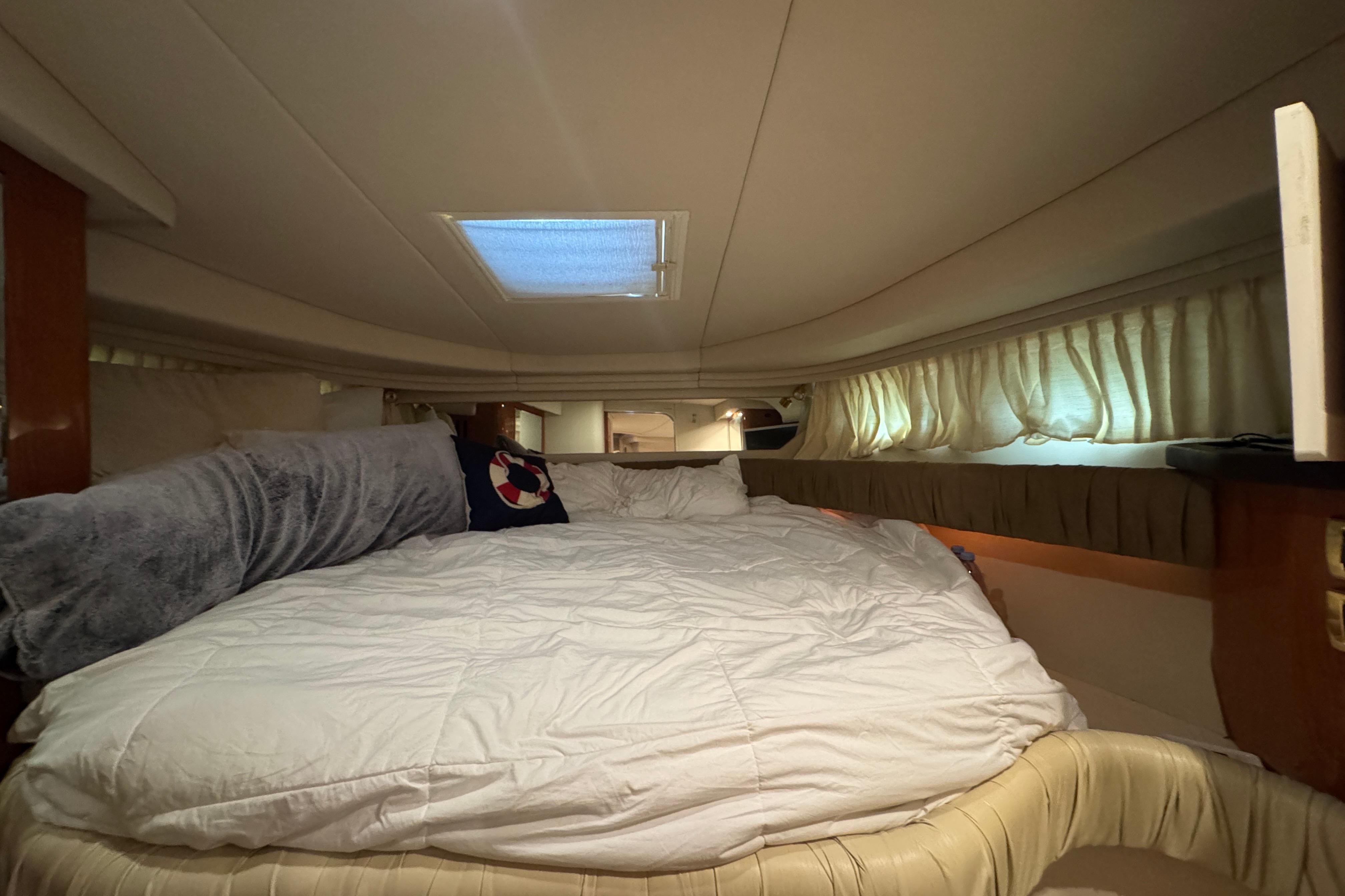 Interior cabin of 2001 Sea Ray 380 Sundancer with cozy bedding and curtains.
