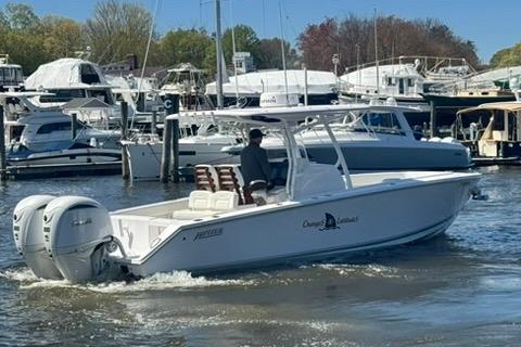 2023 Jupiter 30 boat cruising in a marina with multiple yachts docked.