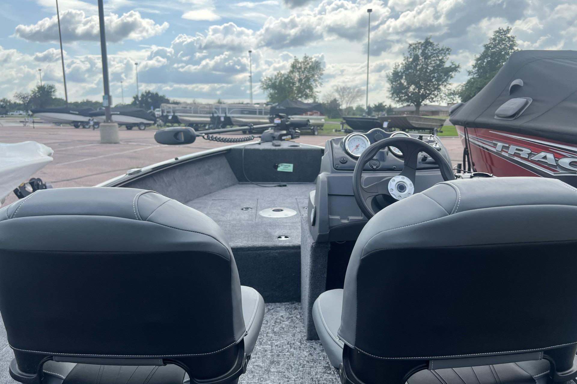 2026 Tracker Super Guide V-16 SC boat interior with steering wheel and seats, parked outdoors.
