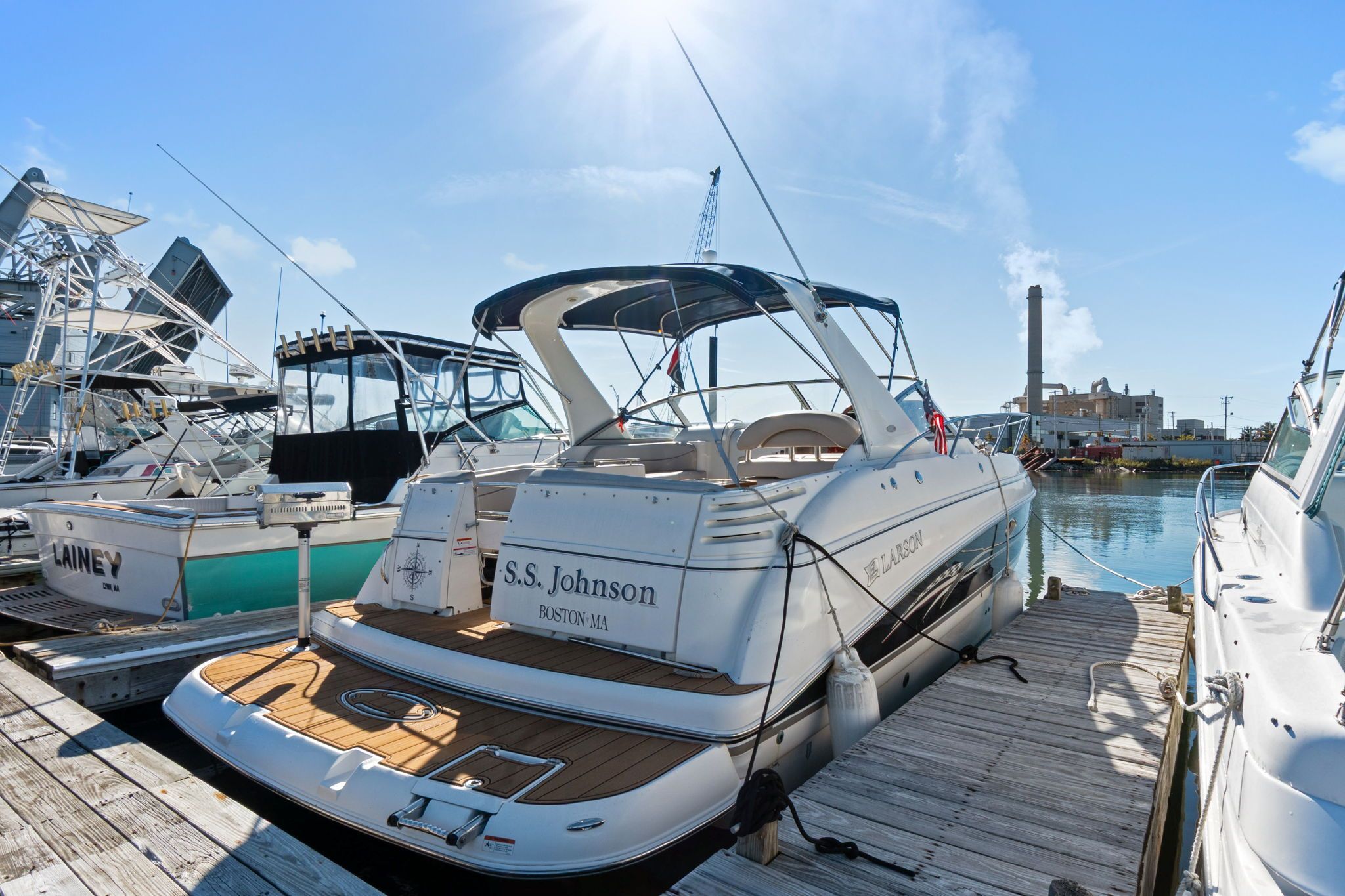 A 2007 Larson Cabrio 330 docked in a sunny marina, surrounded by other boats.