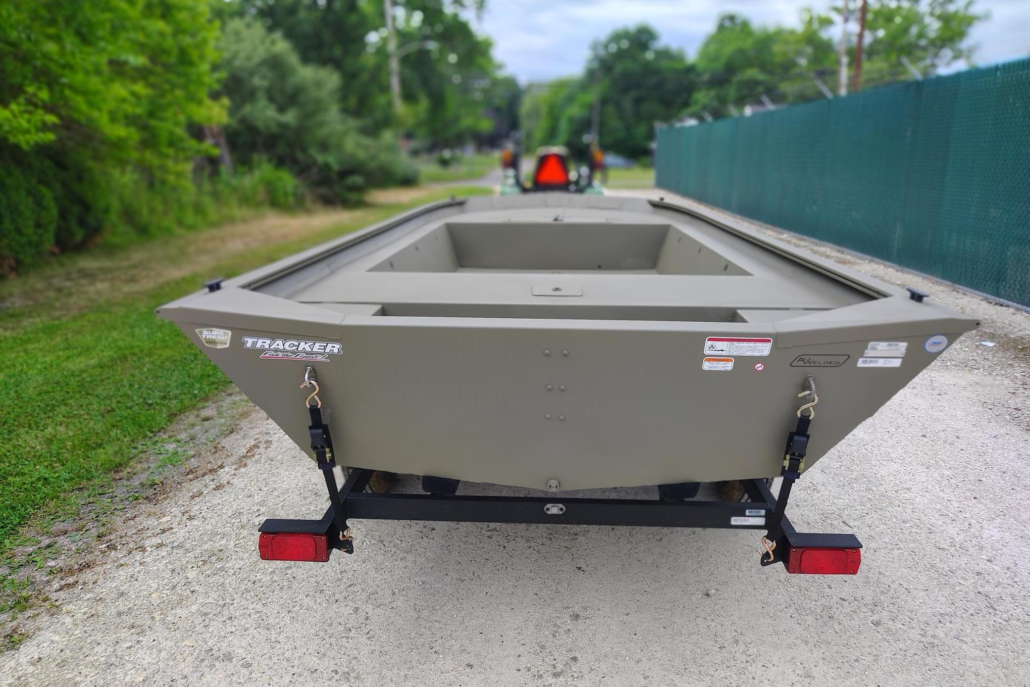 2026 Tracker Grizzly 1754 Utility boat on trailer, parked on gravel path.