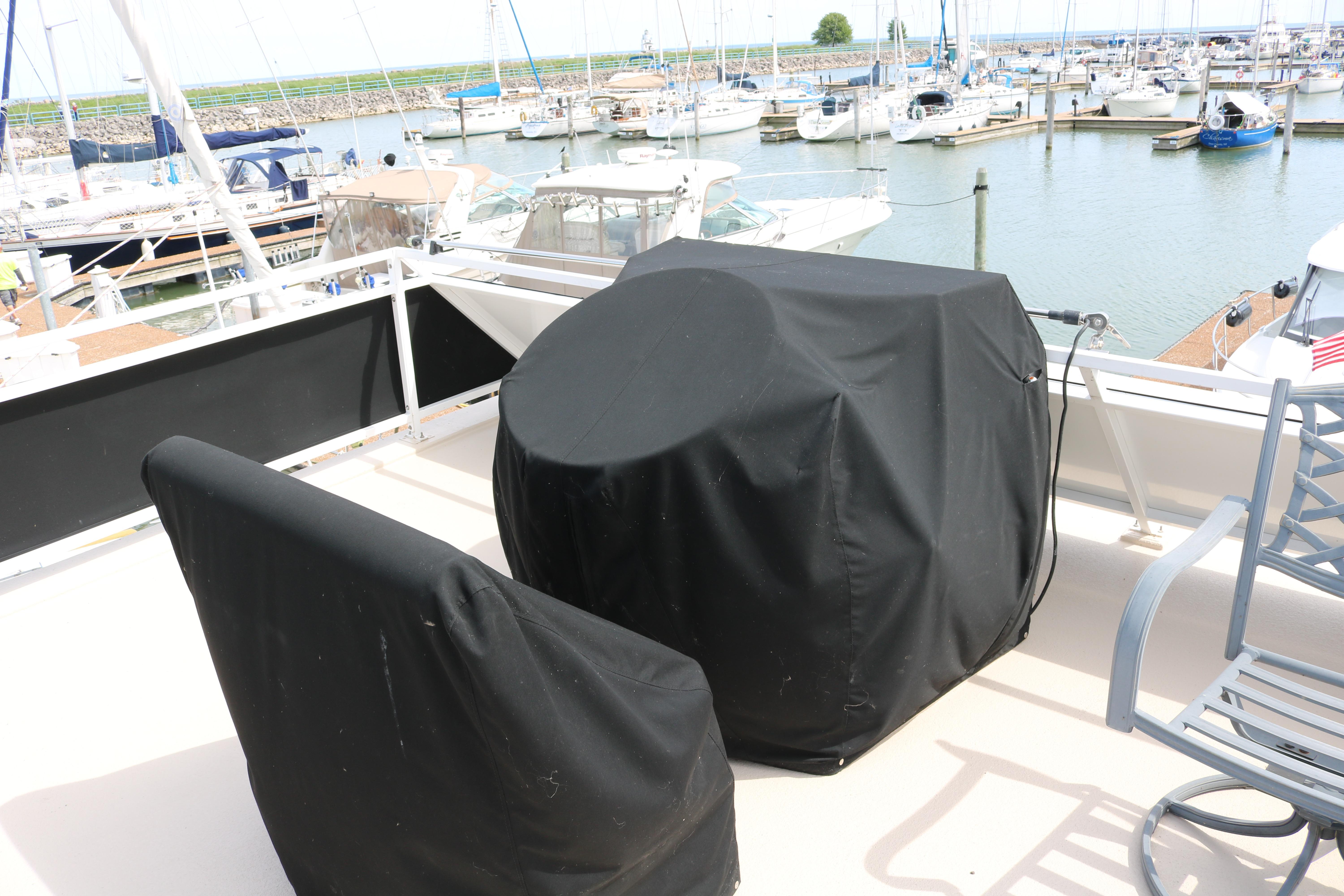 Flybridge of 2010 Skipperliner 480, covered furniture, overlooking marina with docked boats.
