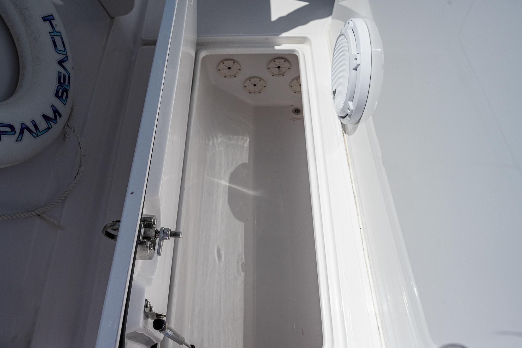 Open storage compartment on 2023 Jupiter 38 boat, featuring a white interior and secure latch.