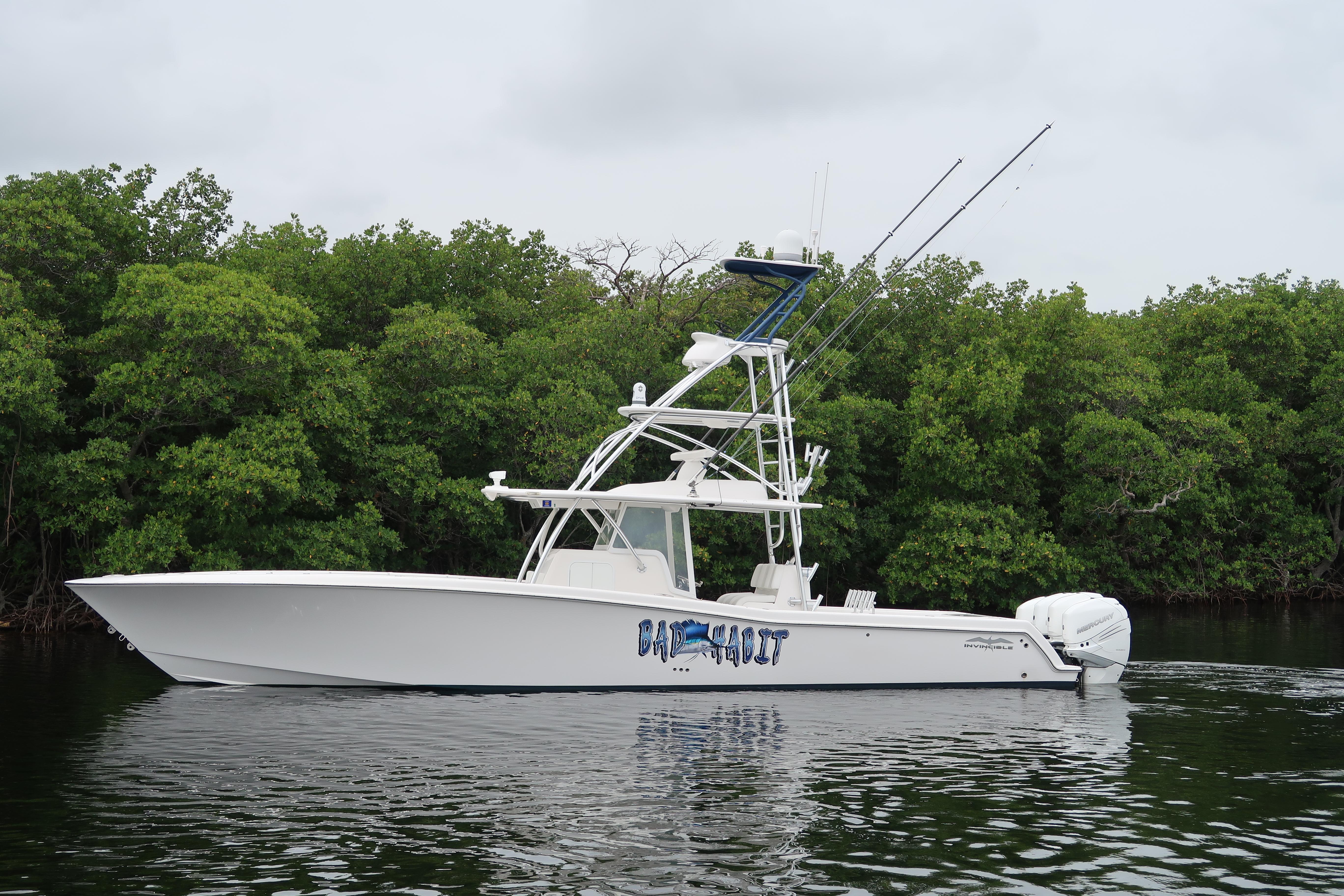 2016 Invincible 42 Open Fisherman boat on calm water near lush greenery.