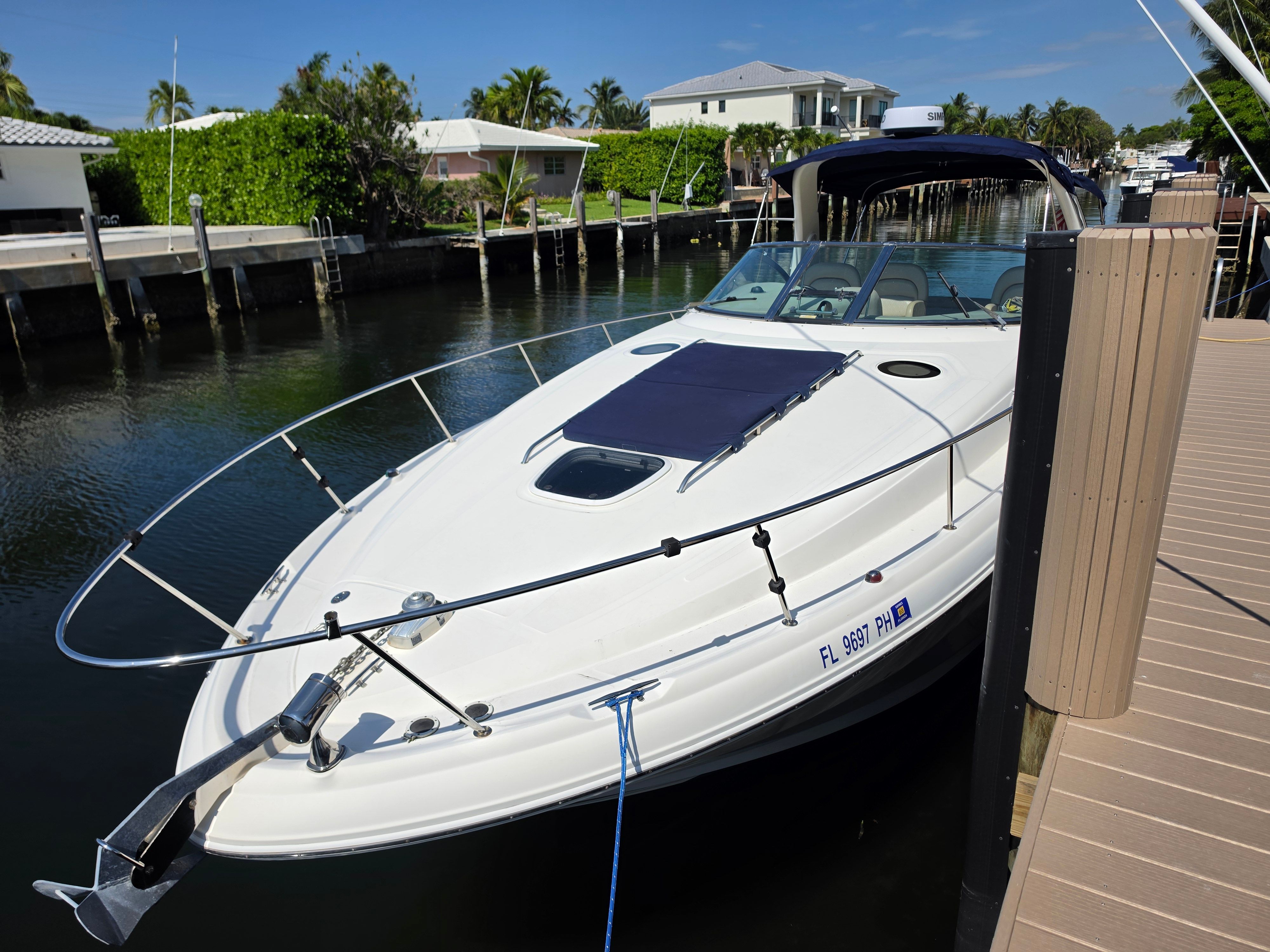 A 2004 Sea Ray 340 Sundancer is docked along a calm canal.