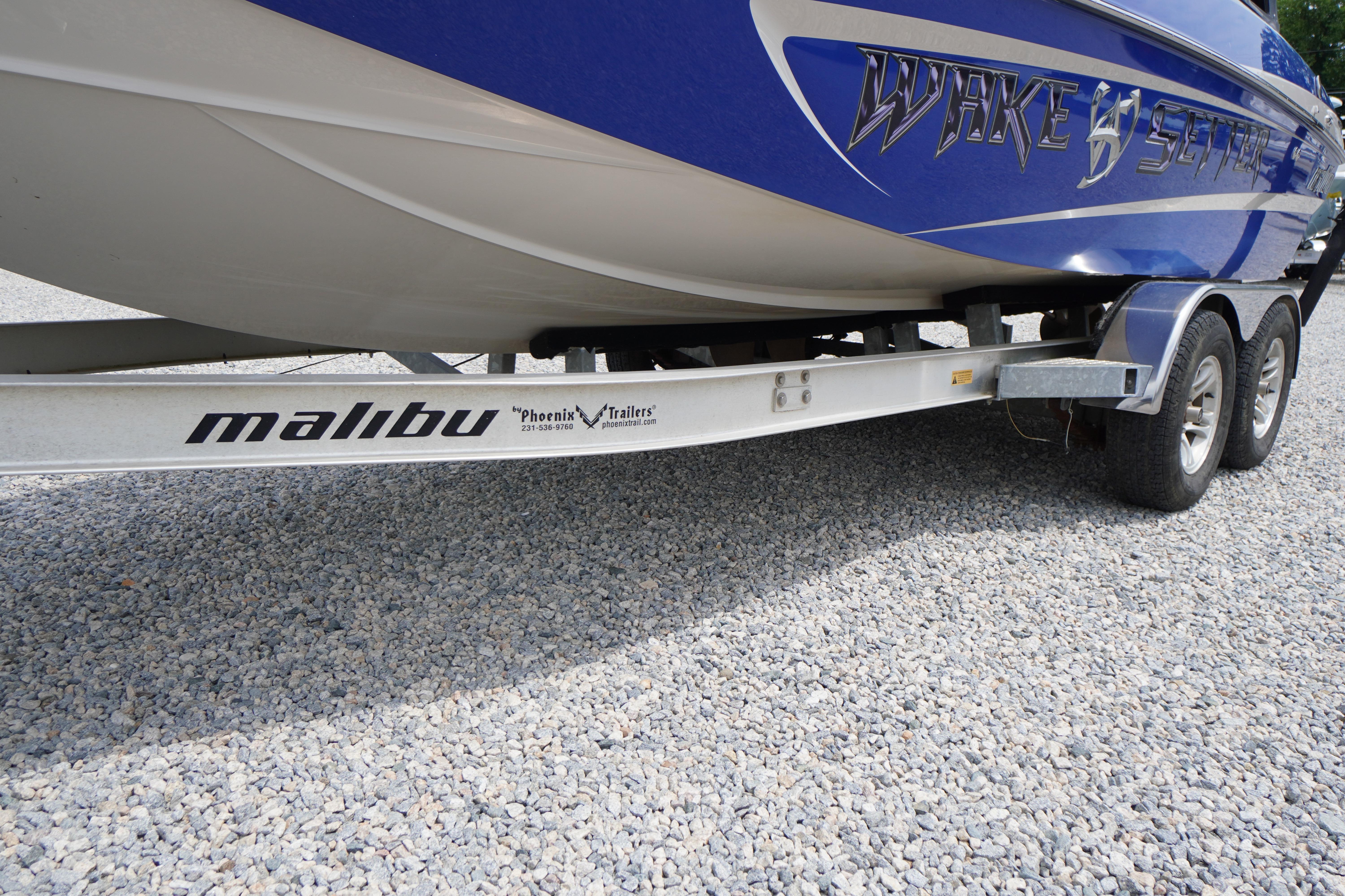 2011 Malibu Wakesetter 21 VLX boat on trailer, blue hull, gravel background.