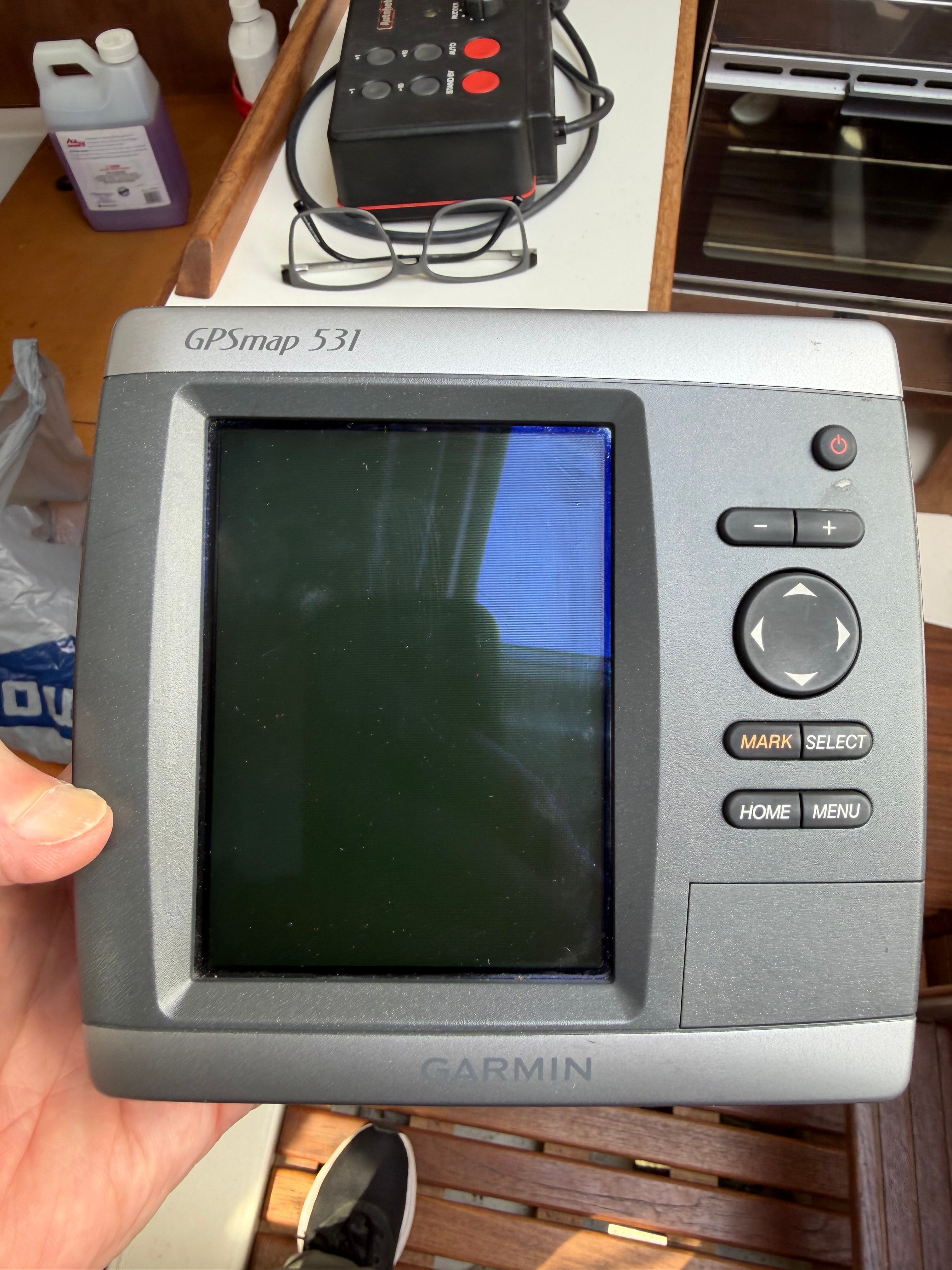 A GPSmap 531 device is held in hand, surrounded by boat interior.