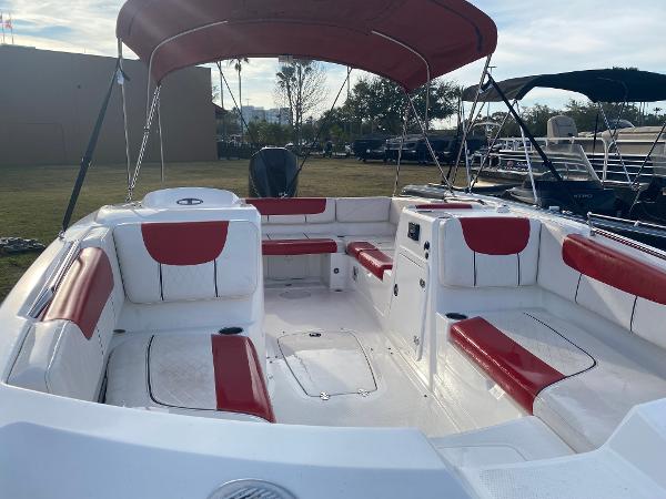 2022 Tahoe 2150 boat with red and white seating, under a canopy, docked outdoors.