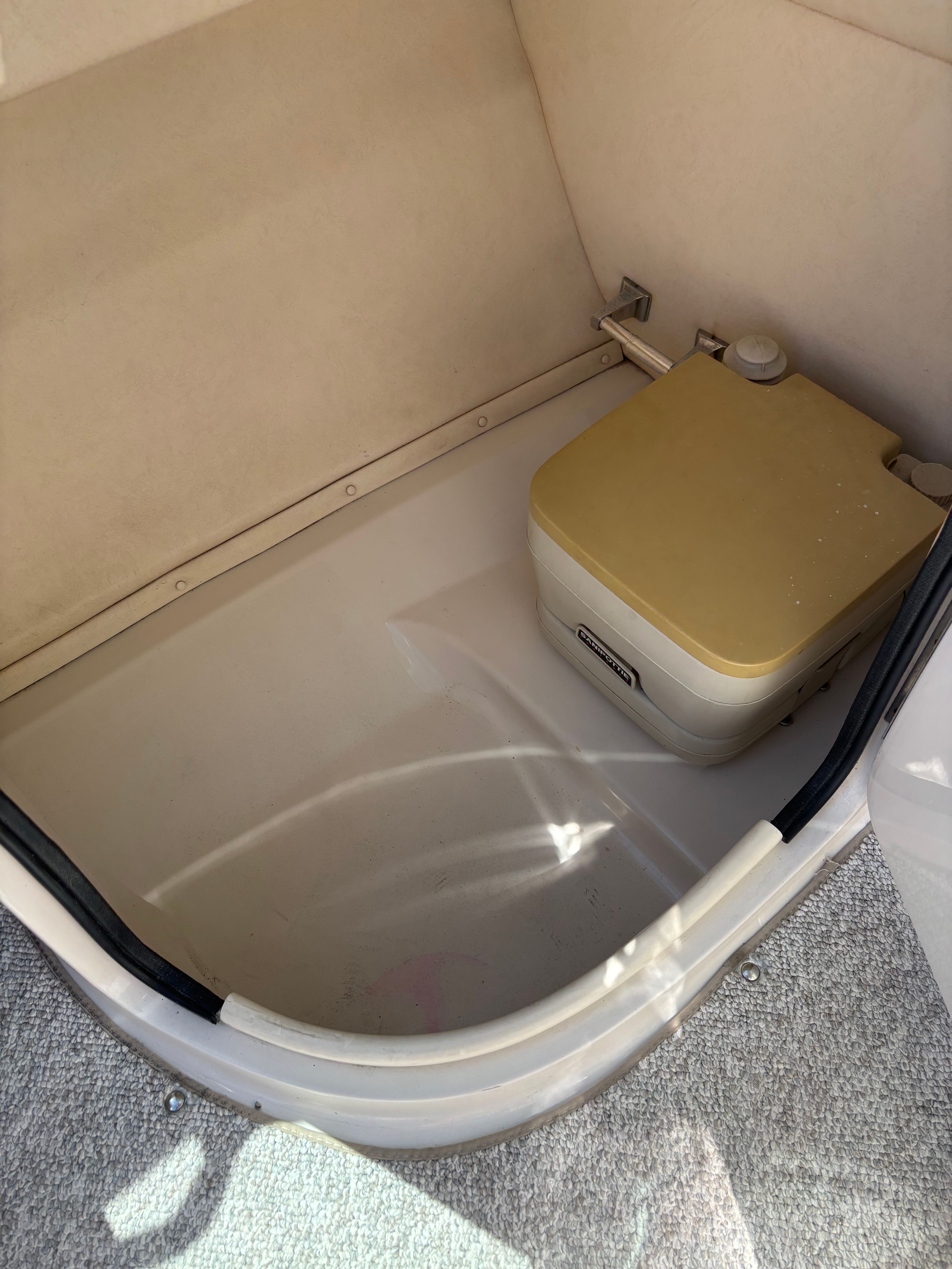 A portable boat toilet in a small compartment.