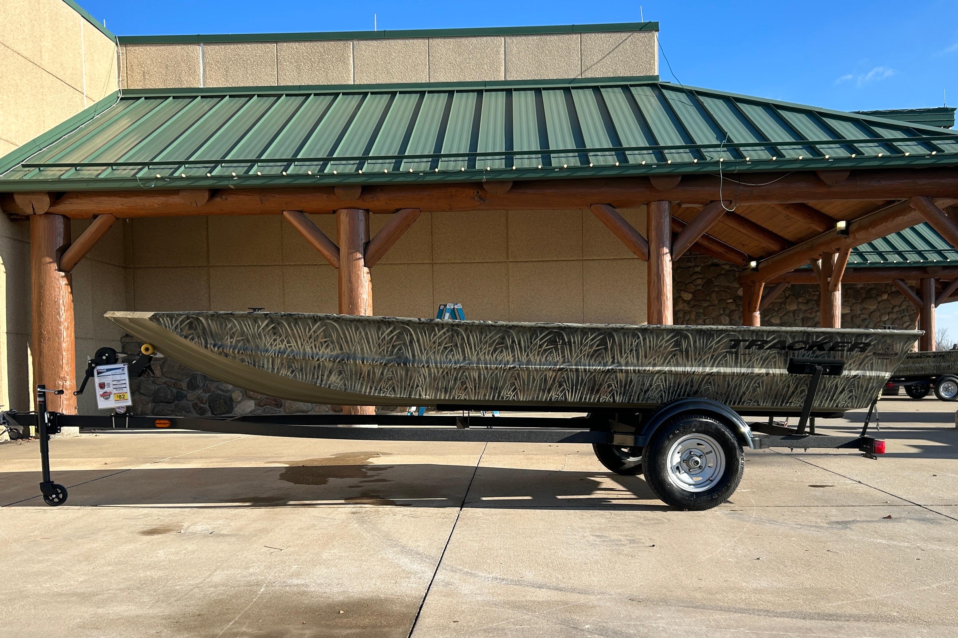 2026 Tracker Grizzly 1754 Utility boat on trailer, parked outside a building.