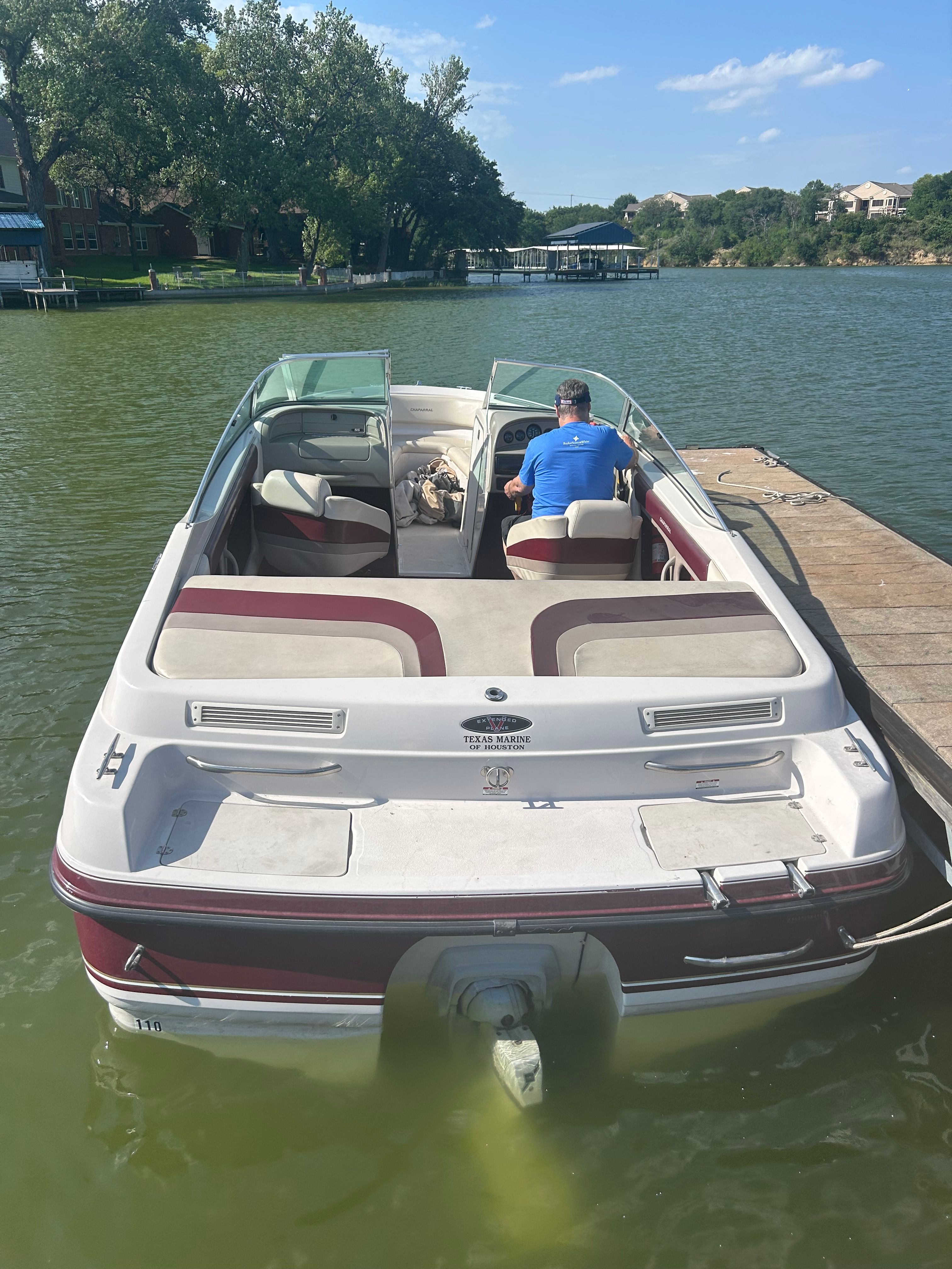 A 1995 Chaparral 2330 boat docked at a pier on a calm lake.