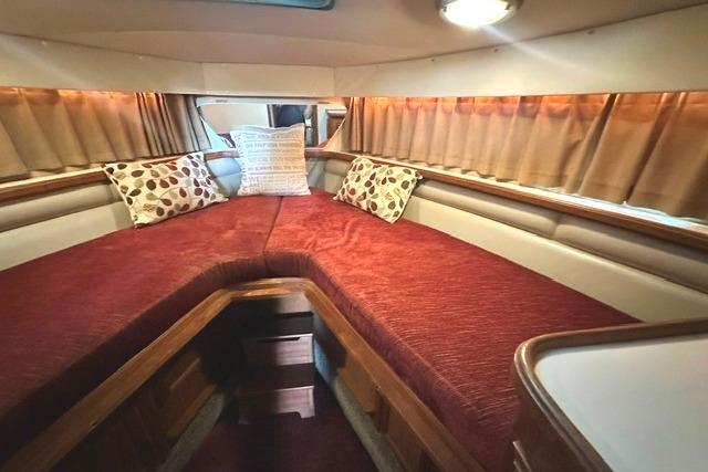 1989 Carver 32 Aft Cabin Motor Yacht interior with red bedding and decorative pillows.