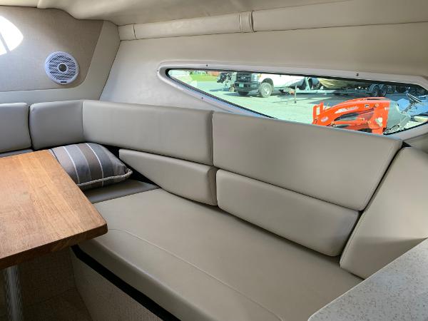 Interior of a 2017 Regal 26 Express with beige upholstered sofa and wooden table.