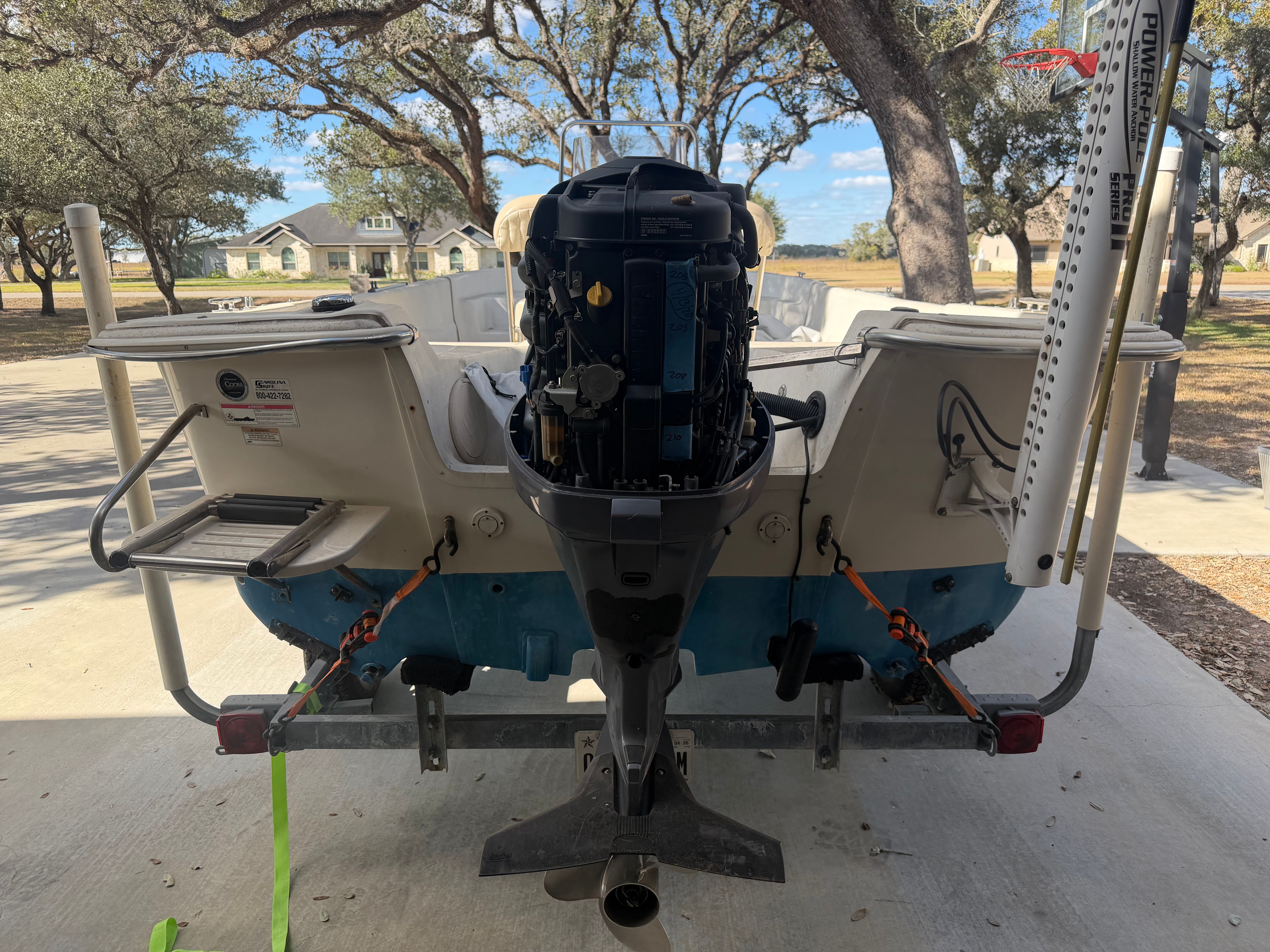 A 2016 Carolina Skiff 178 DLV boat on a trailer in a yard.