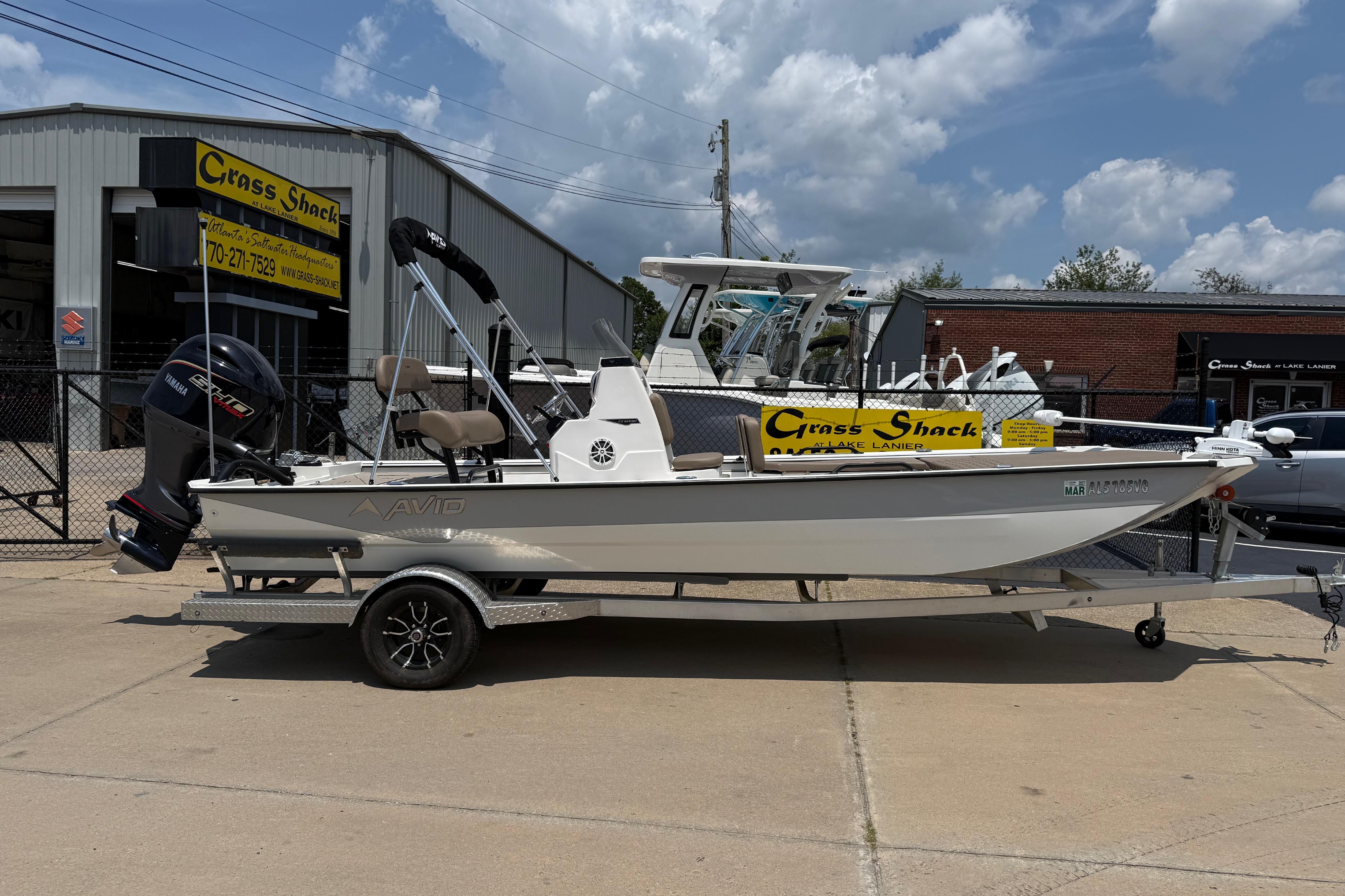 2025 Avid 22 Recon boat on trailer outside dealership under cloudy sky.