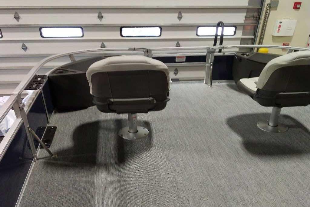 2026 Sun Tracker Bass Buggy 18 DLX interior with swivel seats in a garage setting.