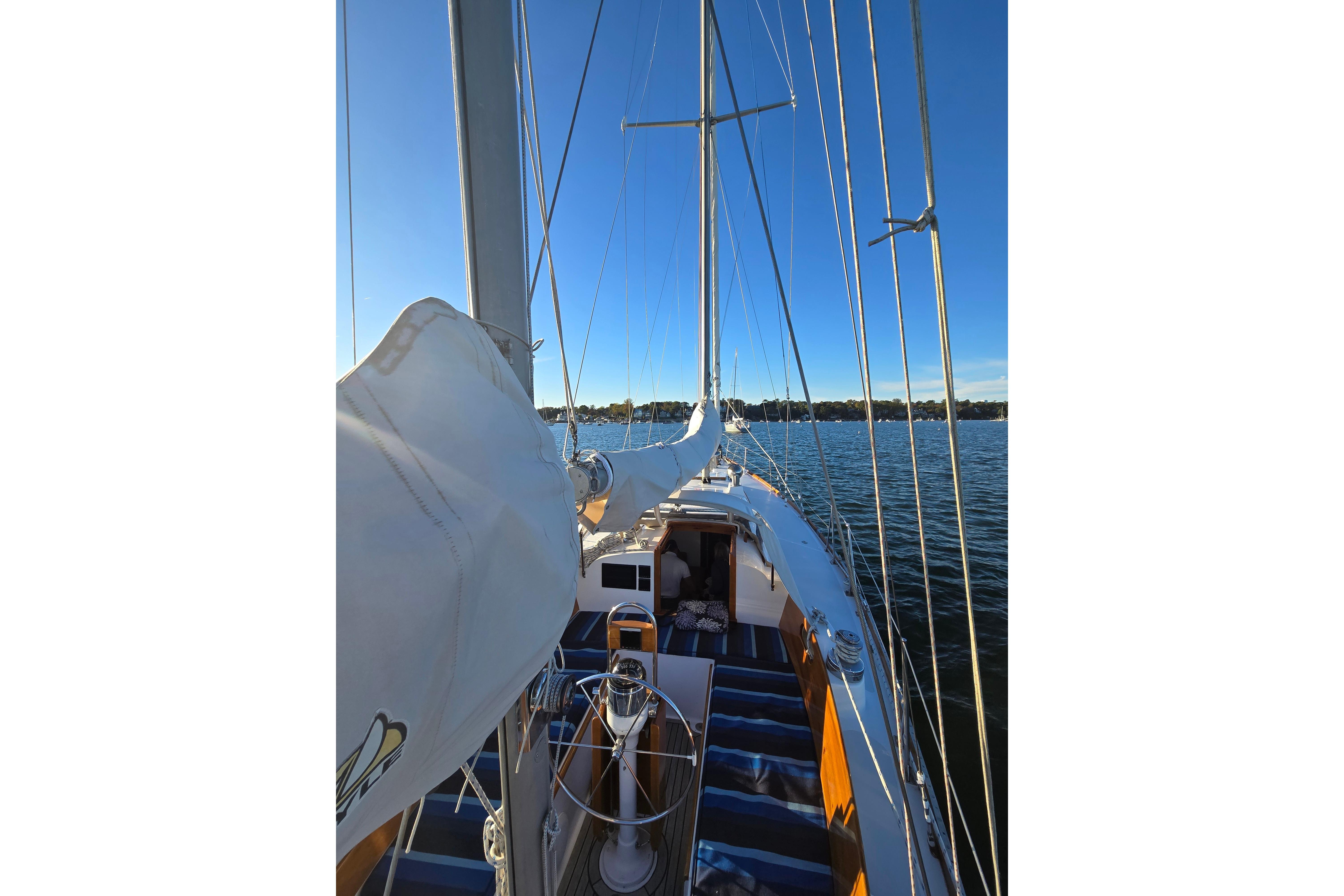 1970 Hinckley Bermuda 40 sailboat on calm water under clear blue sky.