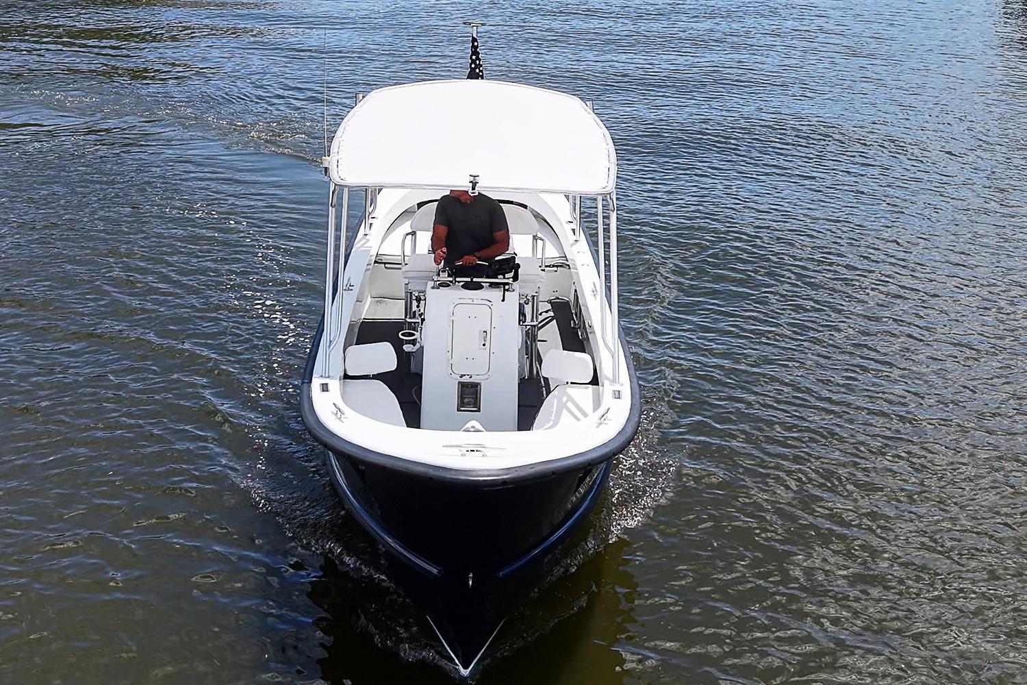 Custom 1969 boat cruising on water with a canopy and a person steering.