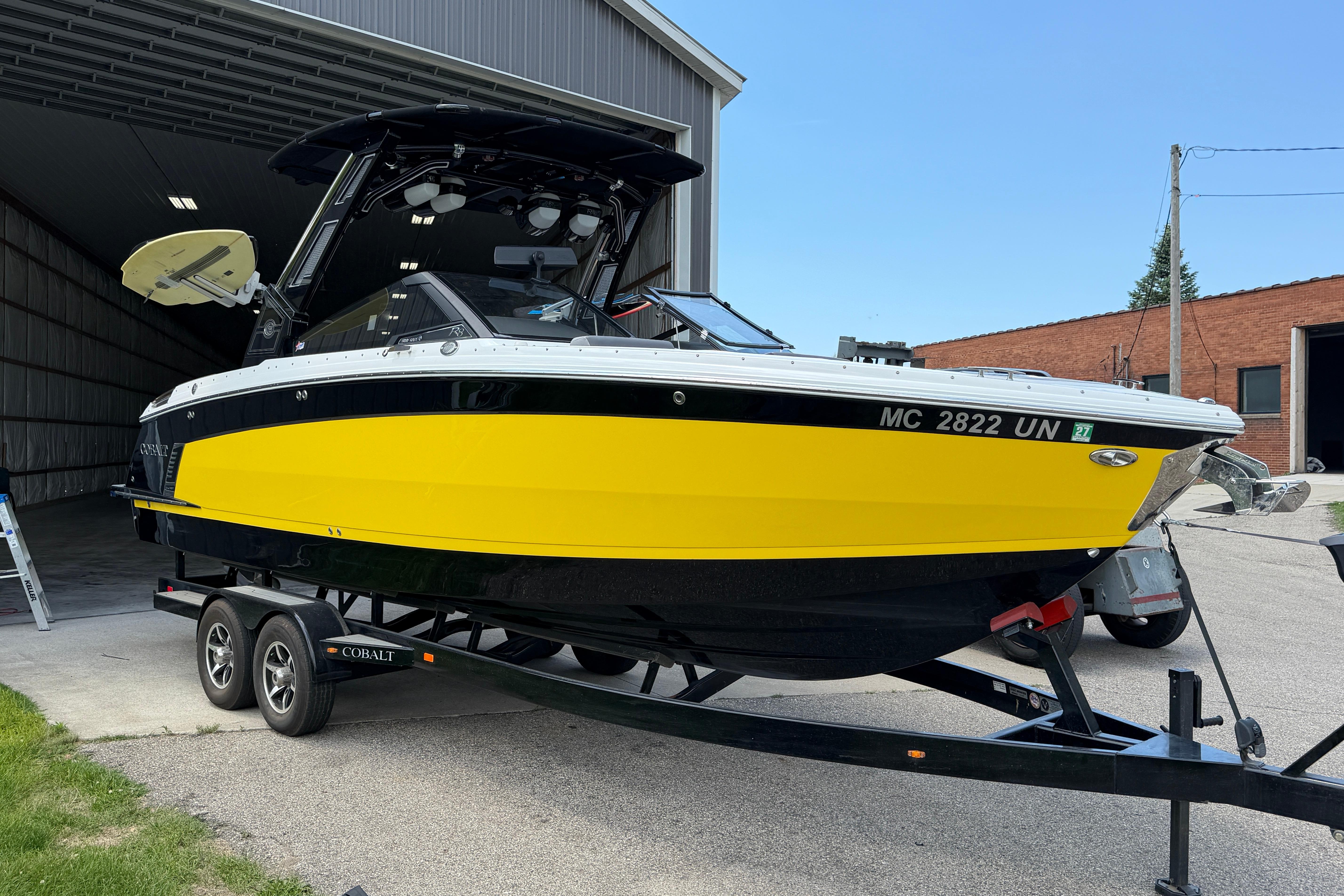 2021 Cobalt R8 Surf boat with vibrant yellow hull on a trailer.